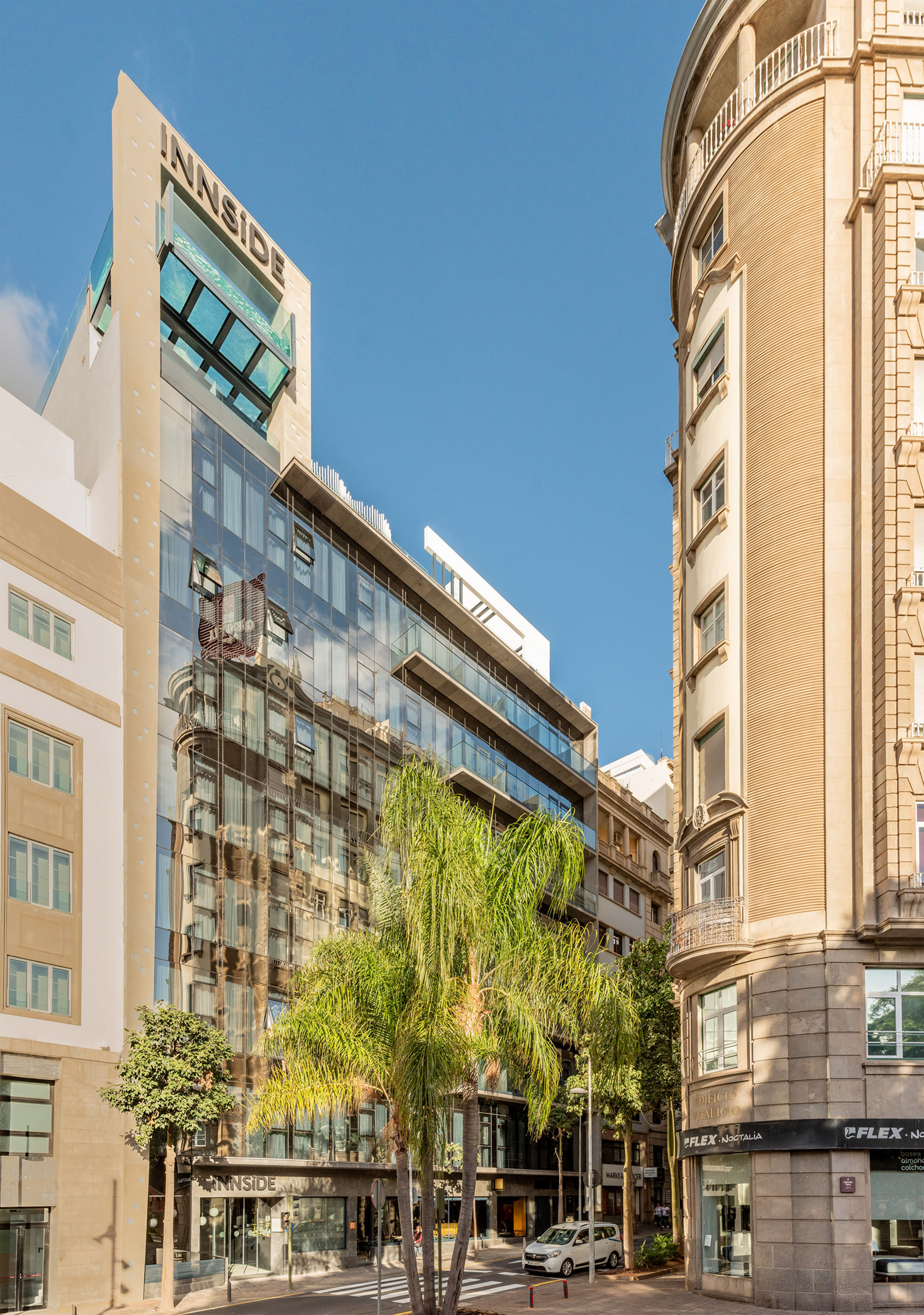 INNSiDE hotel: modern glass building, rooftop pool, palm trees, city street.