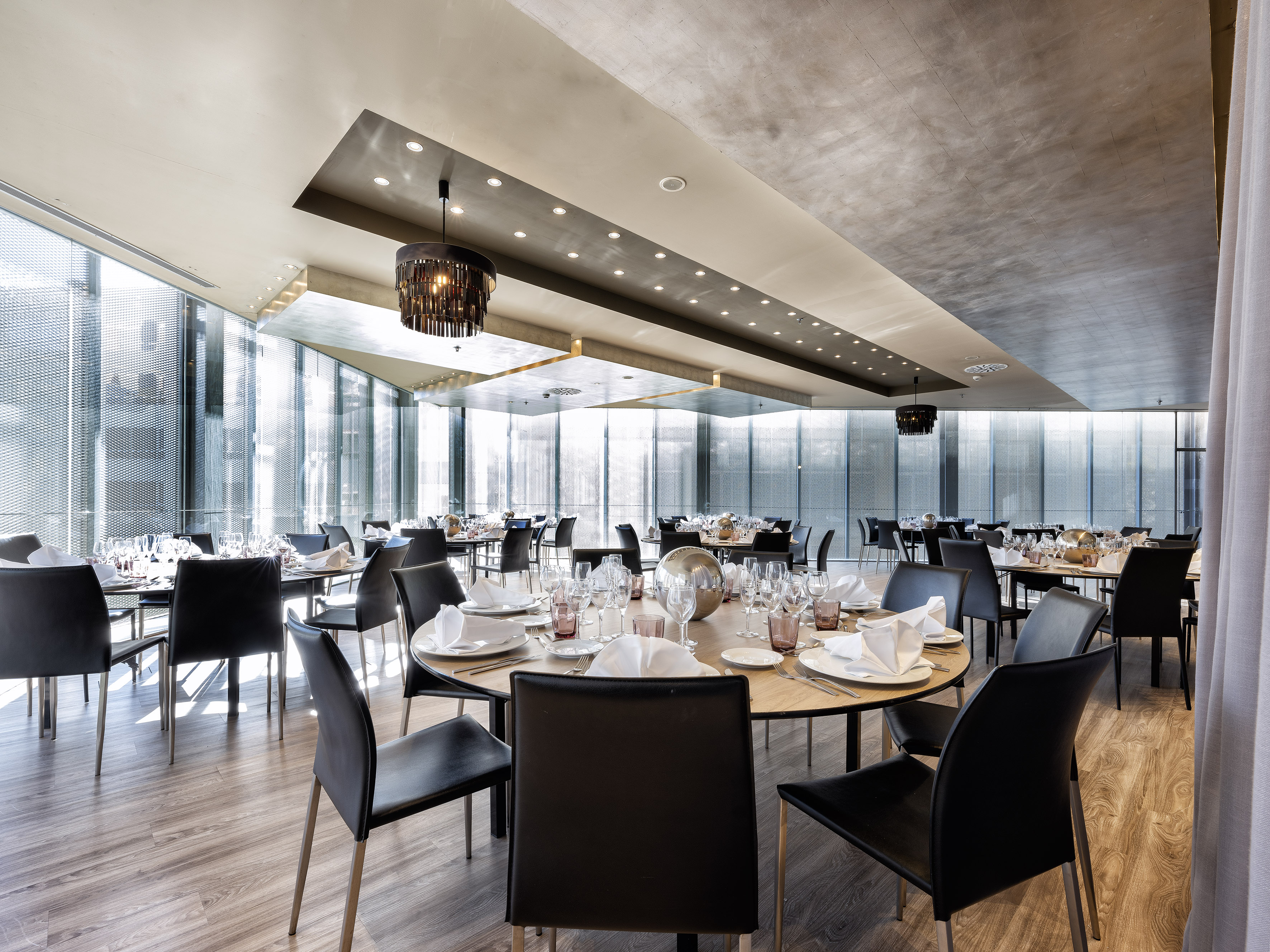 Modern restaurant with set round tables, black chairs, and natural light. - FORUM - فندق برشلونة كوندال مار(Condal Mar) المنتسب لـ Melia, برشلونة