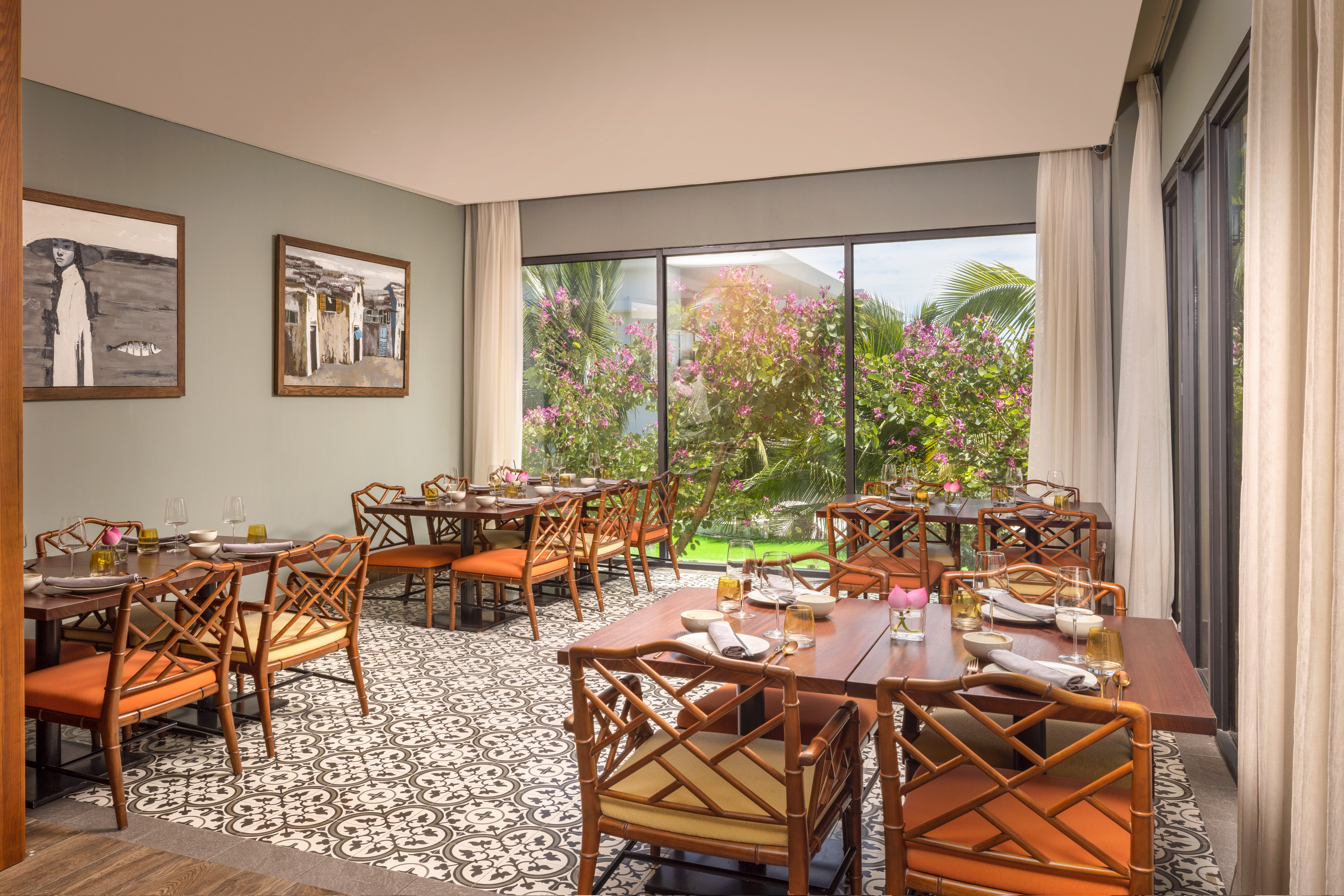 Stylish restaurant dining room overlooking a tropical garden with pink flowers.