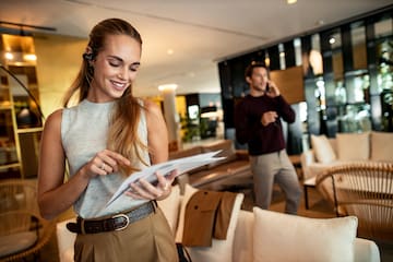 Smiling businesswoman with headphones reviews documents in office.