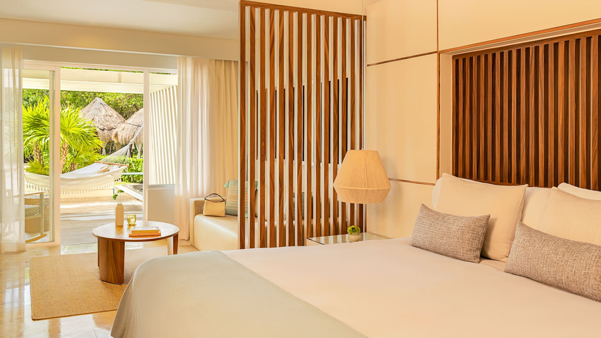 Luxury hotel bedroom with tropical patio, hammock, and garden view.