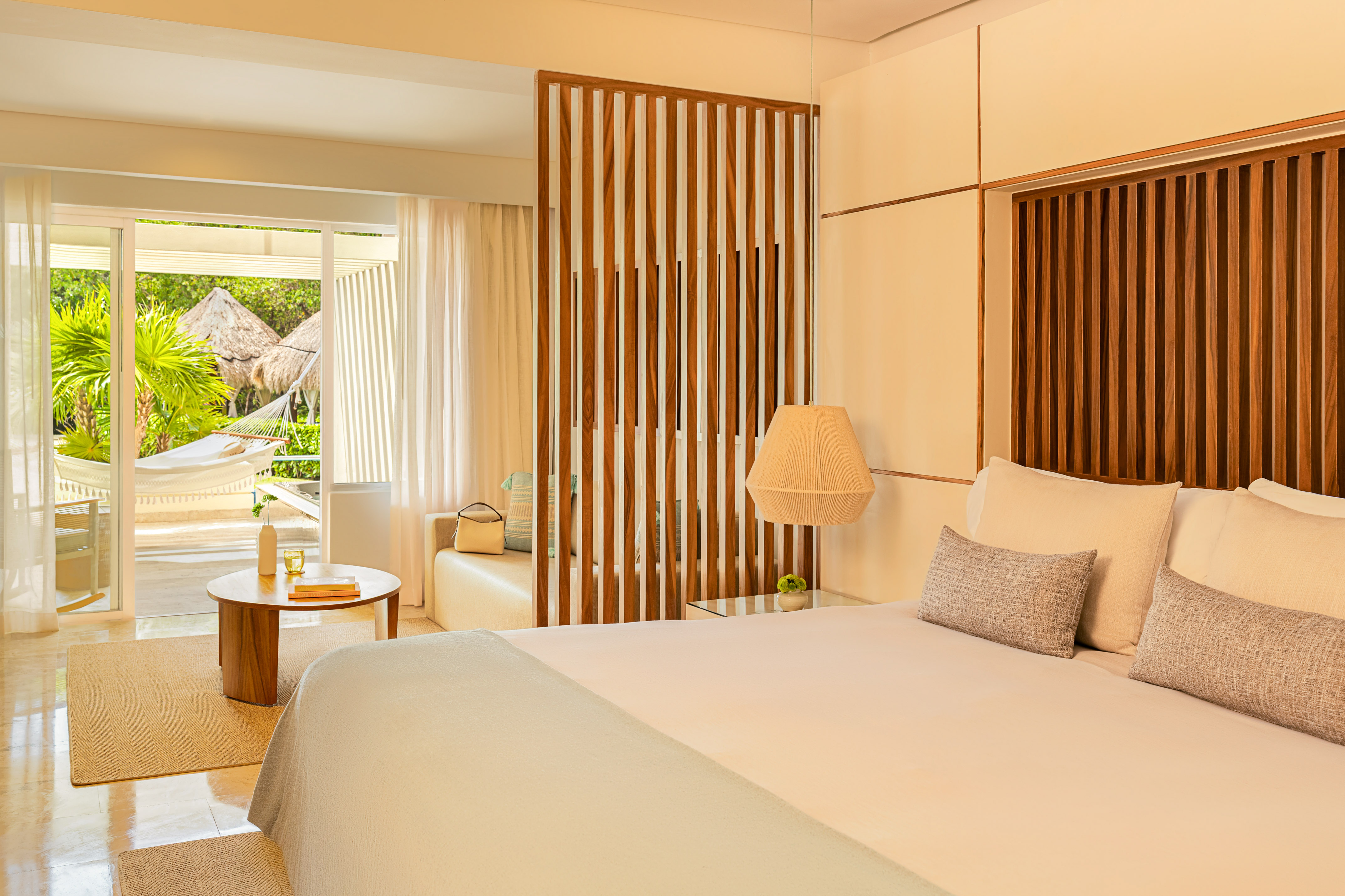 Luxury hotel bedroom with tropical patio, hammock, and garden view.