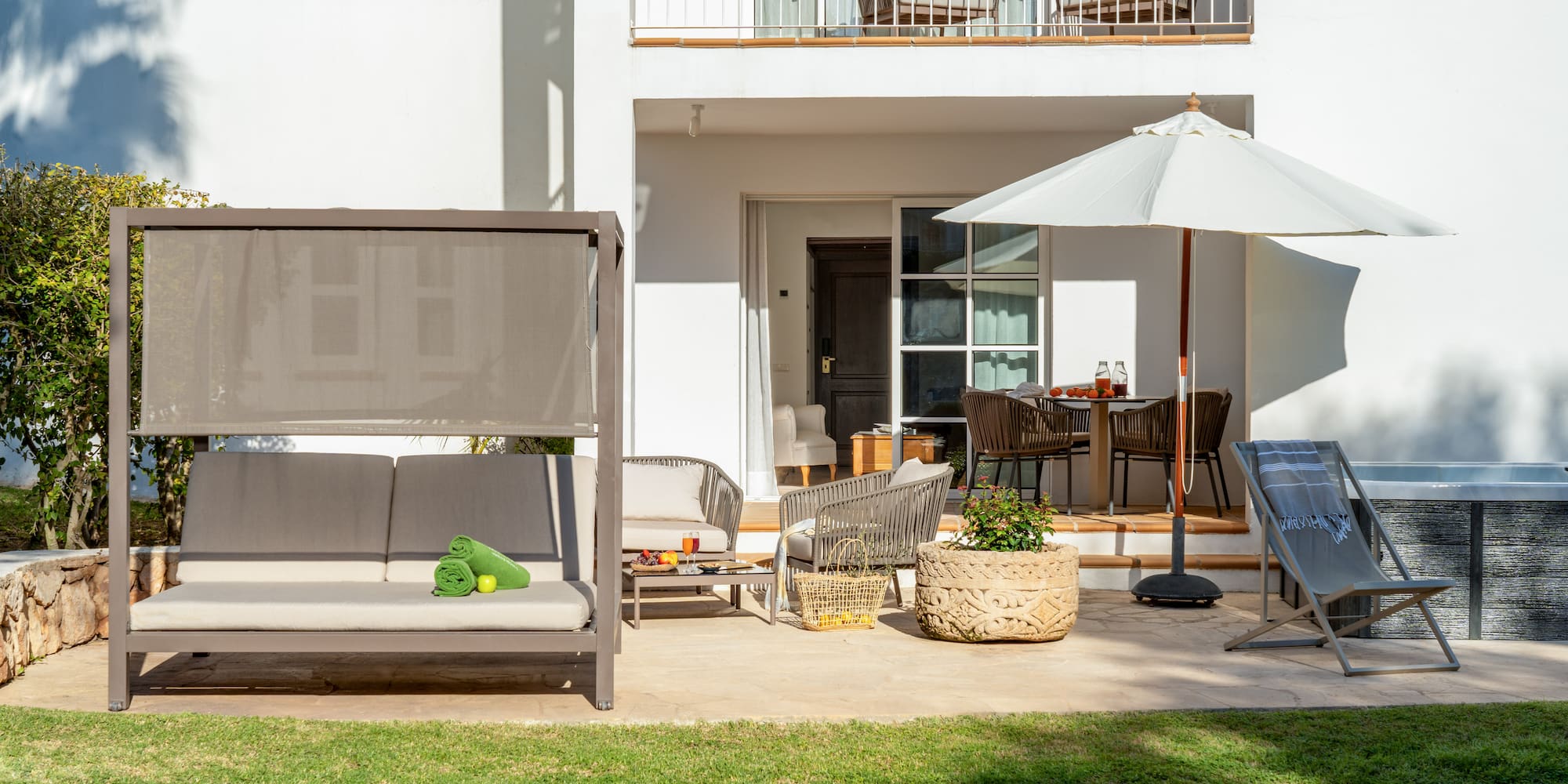a patio with a white building and a white patio with a white umbrella and a white couch