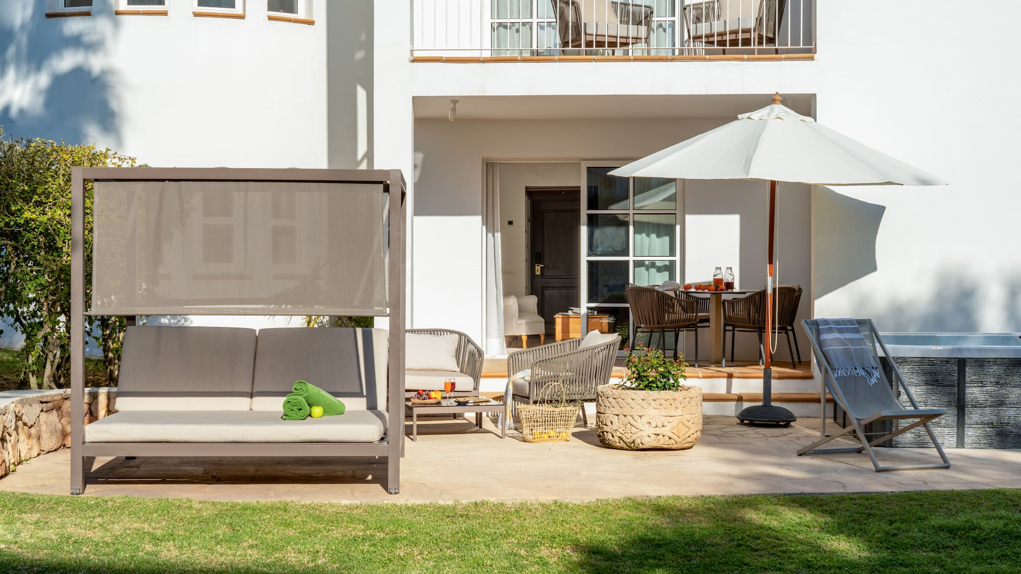 a patio with a white building and a white patio with a white umbrella and a white couch