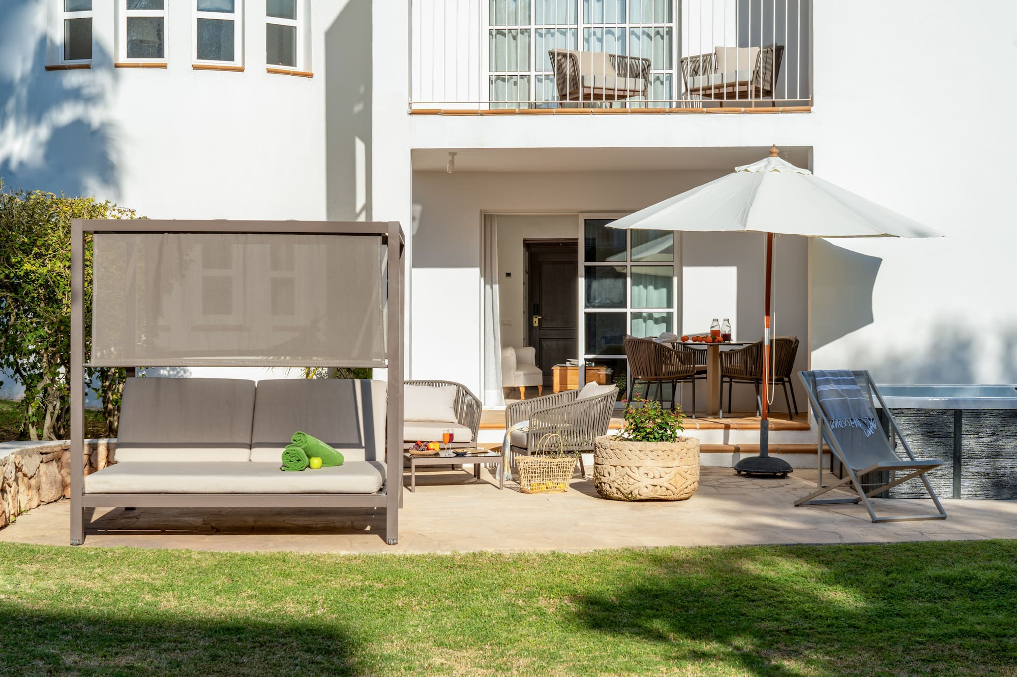a patio with a white building and a white patio with a white umbrella and a white couch