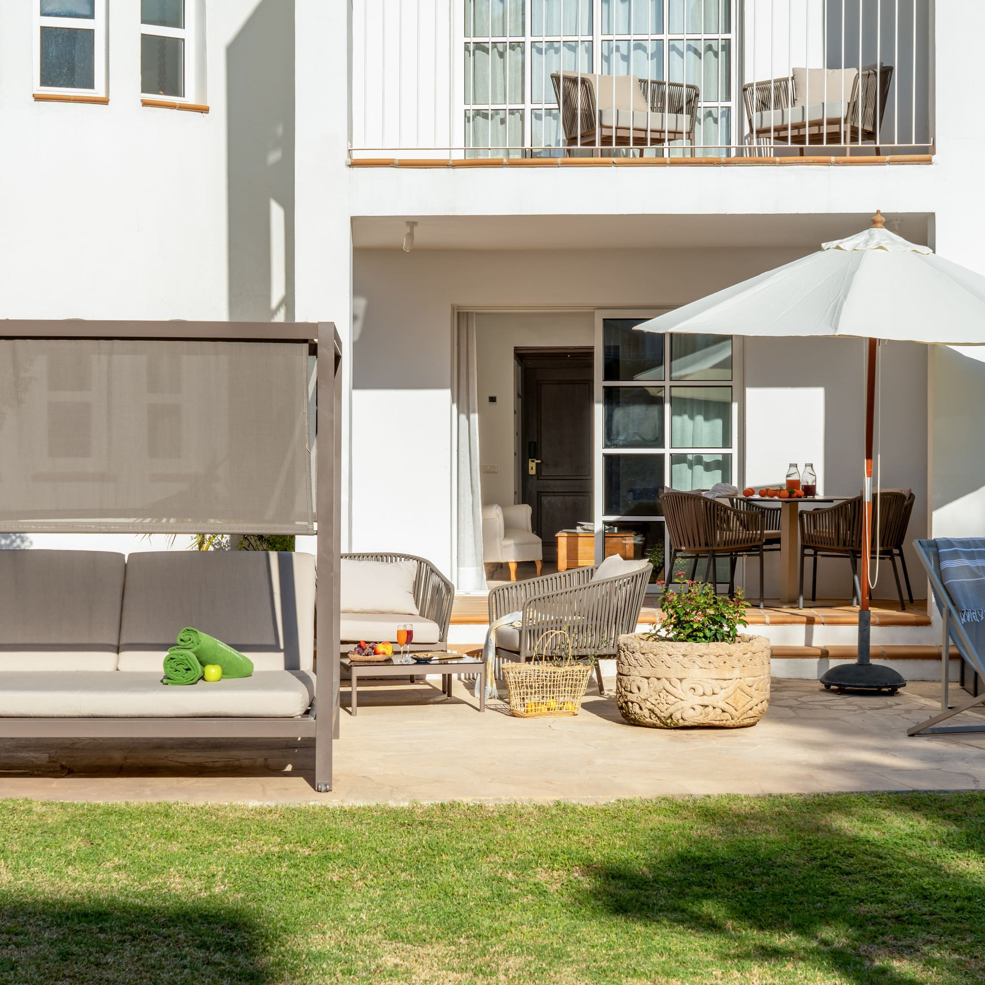 a patio with a white building and a white patio with a white umbrella and a white couch