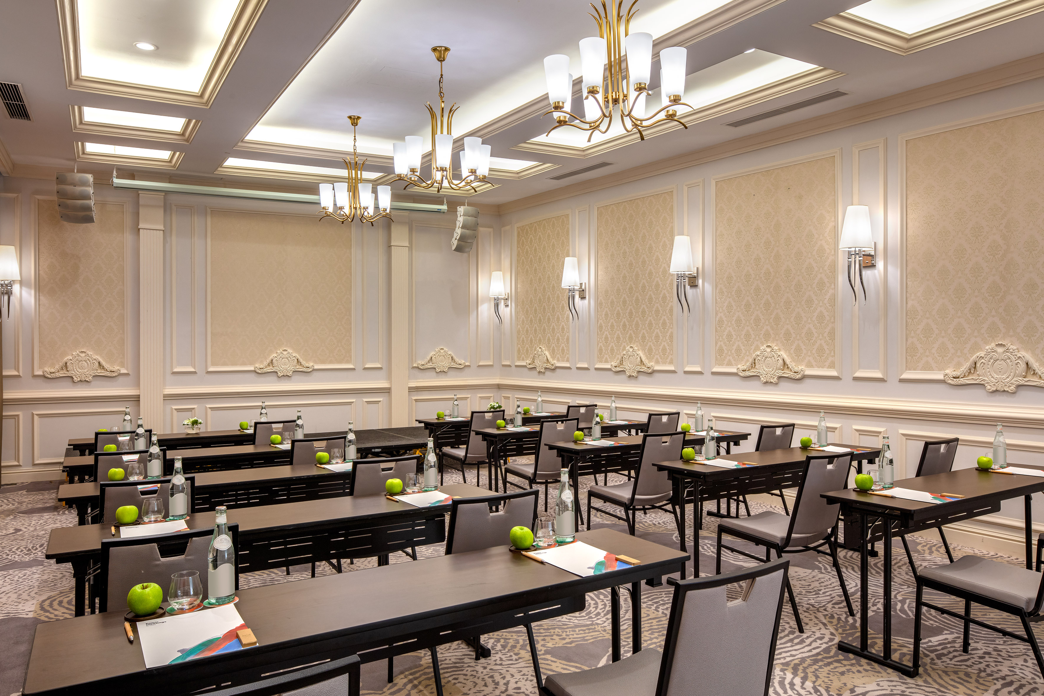 Elegant conference room with rows of individual desks, water, apples.