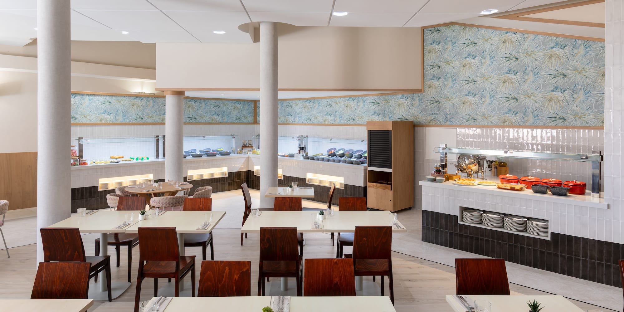 Bright buffet restaurant with food stations, set dining tables, and modern decor.