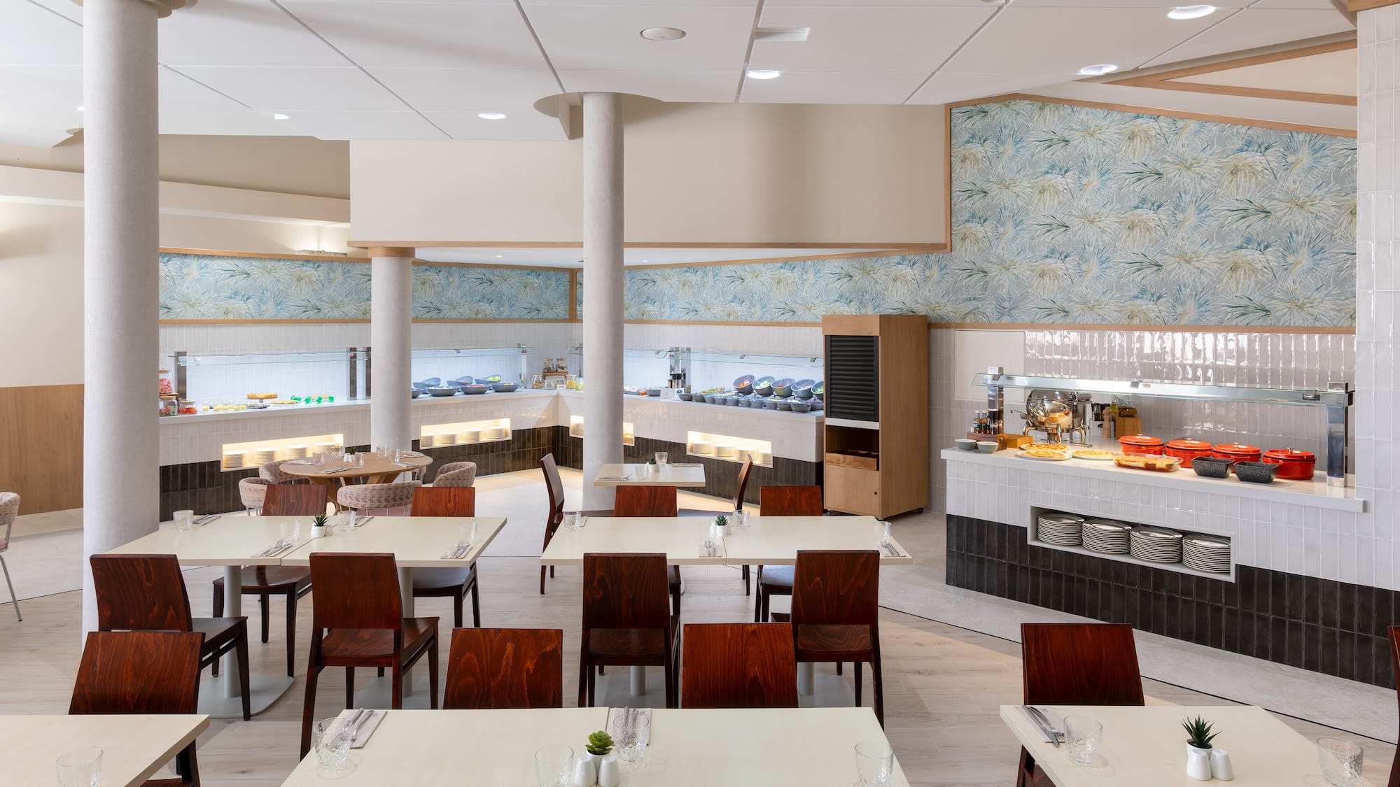 Bright buffet restaurant with food stations, set dining tables, and modern decor.