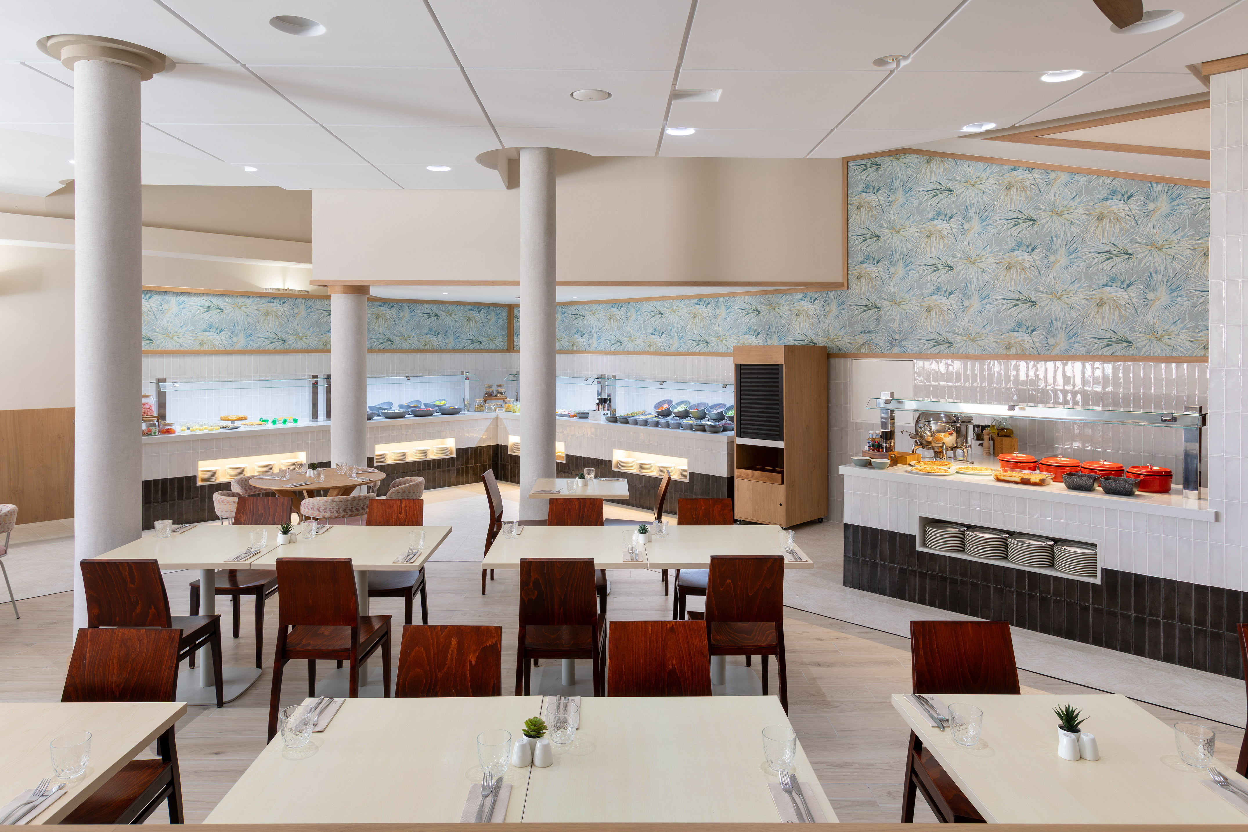 Bright buffet restaurant with food stations, set dining tables, and modern decor.