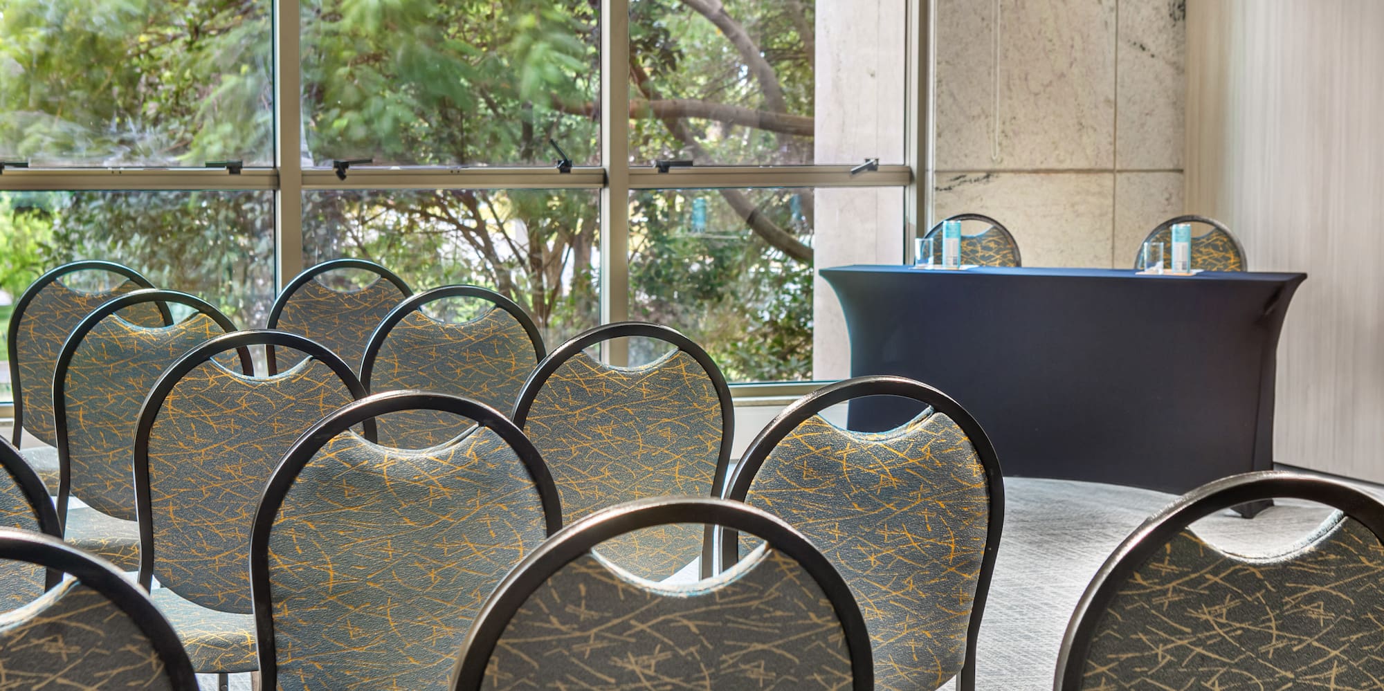 Conference room with empty chairs, presentation table, and large windows.