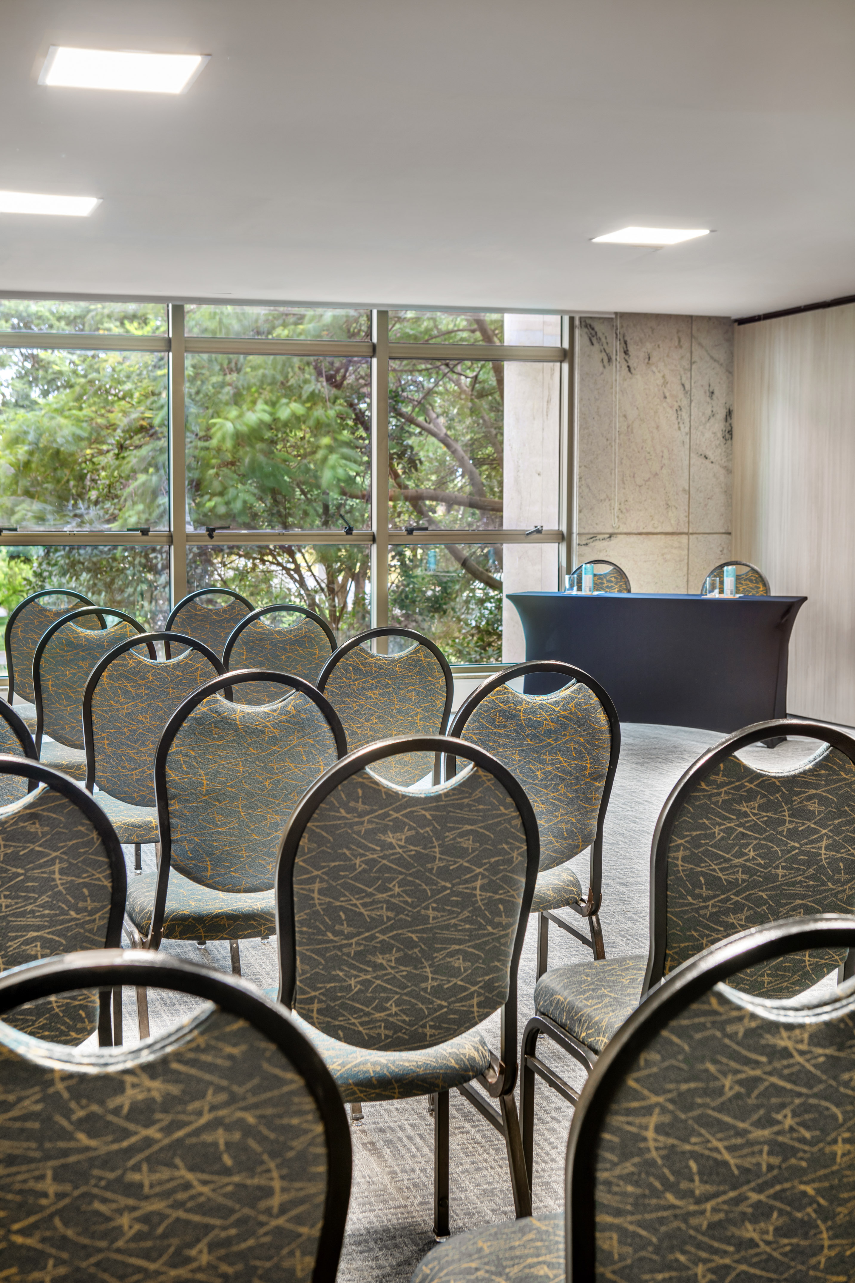 Conference room with empty chairs, presentation table, and large windows.