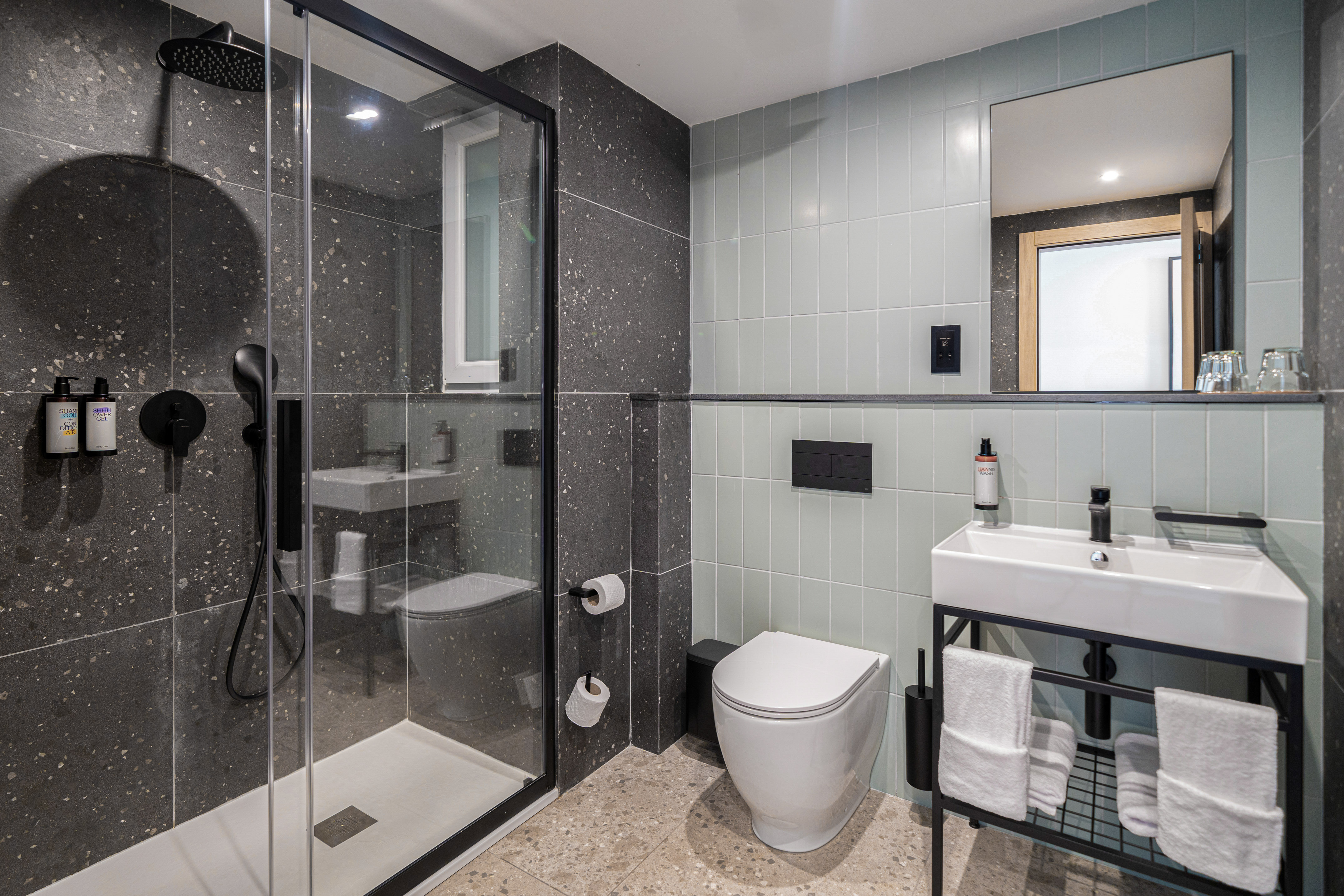 Modern hotel bathroom with glass shower, white toilet, and sink vanity.