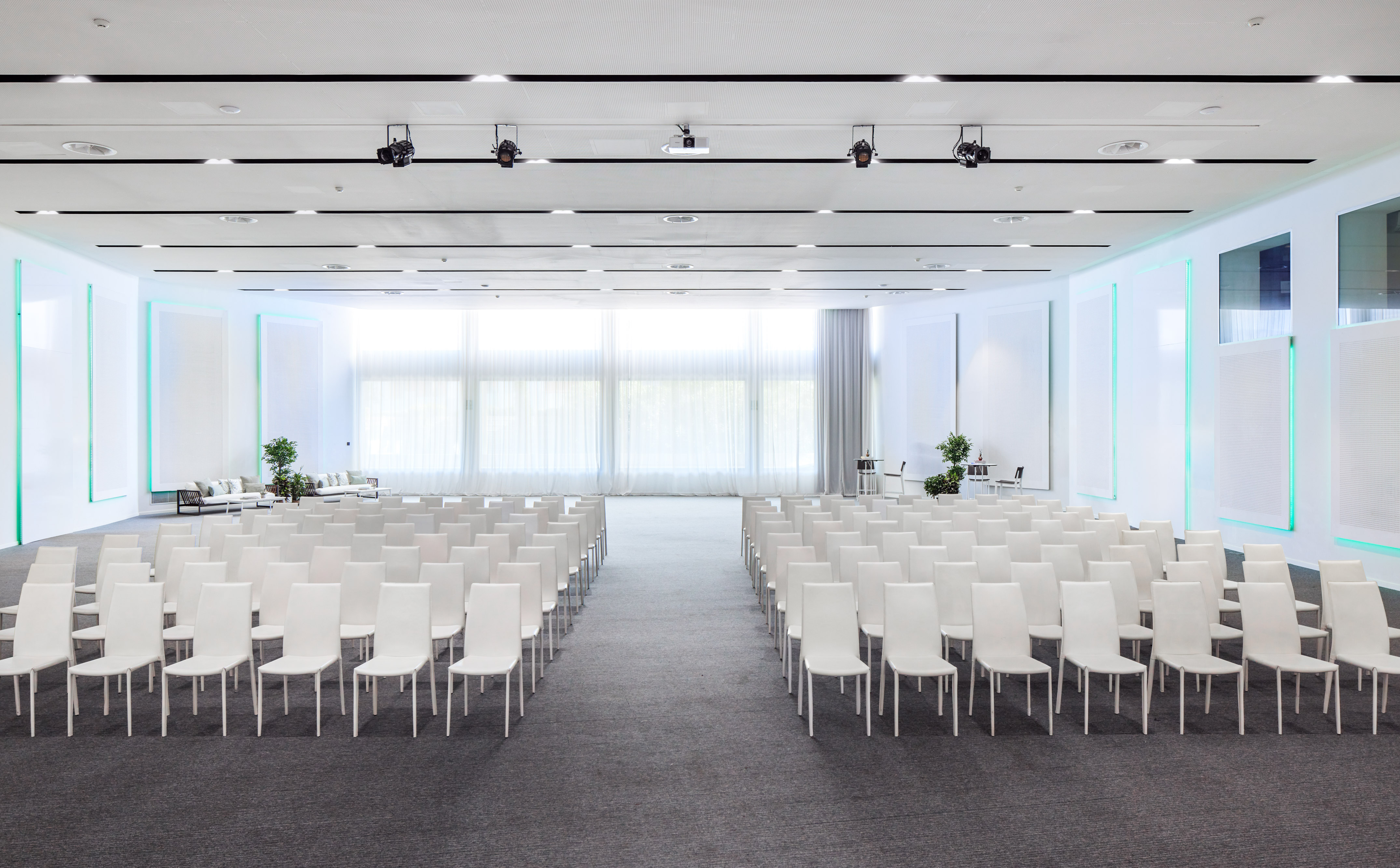 Spacious modern conference room with rows of white chairs and natural light.