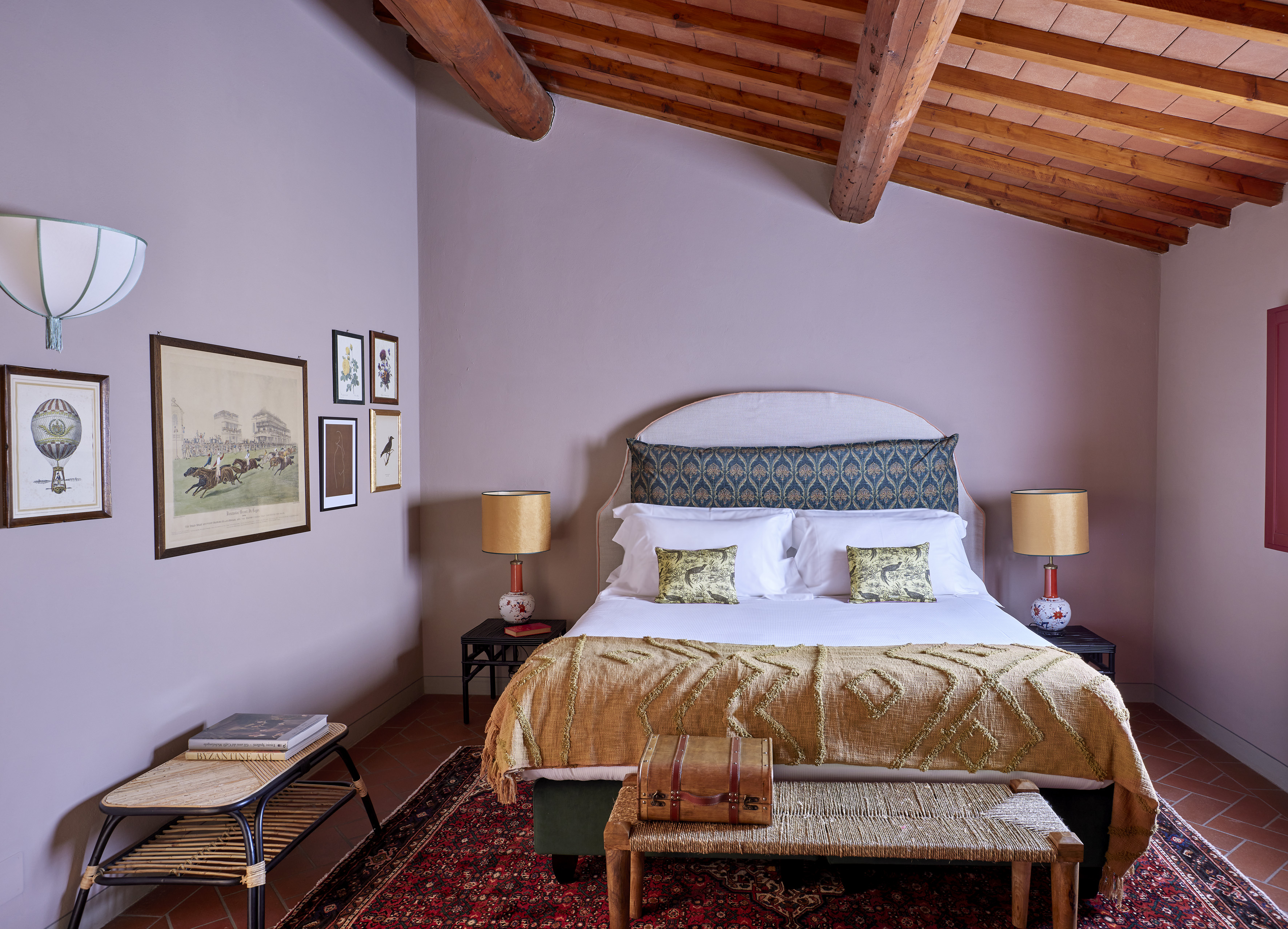 Elegant bedroom with exposed wood beams, patterned bed, and antique decor.