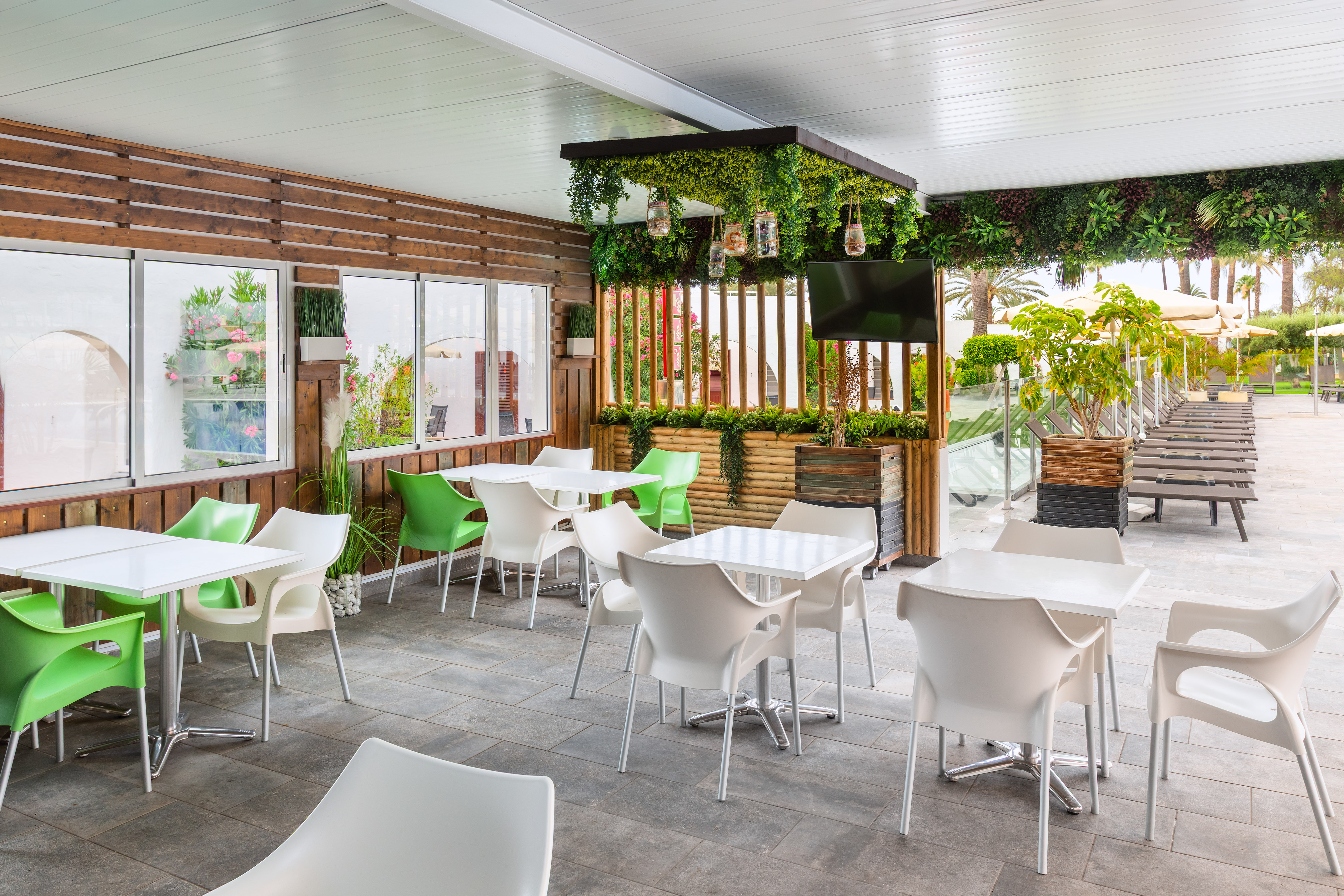 Tropical outdoor dining patio with modern white and green chairs, wooden decor.