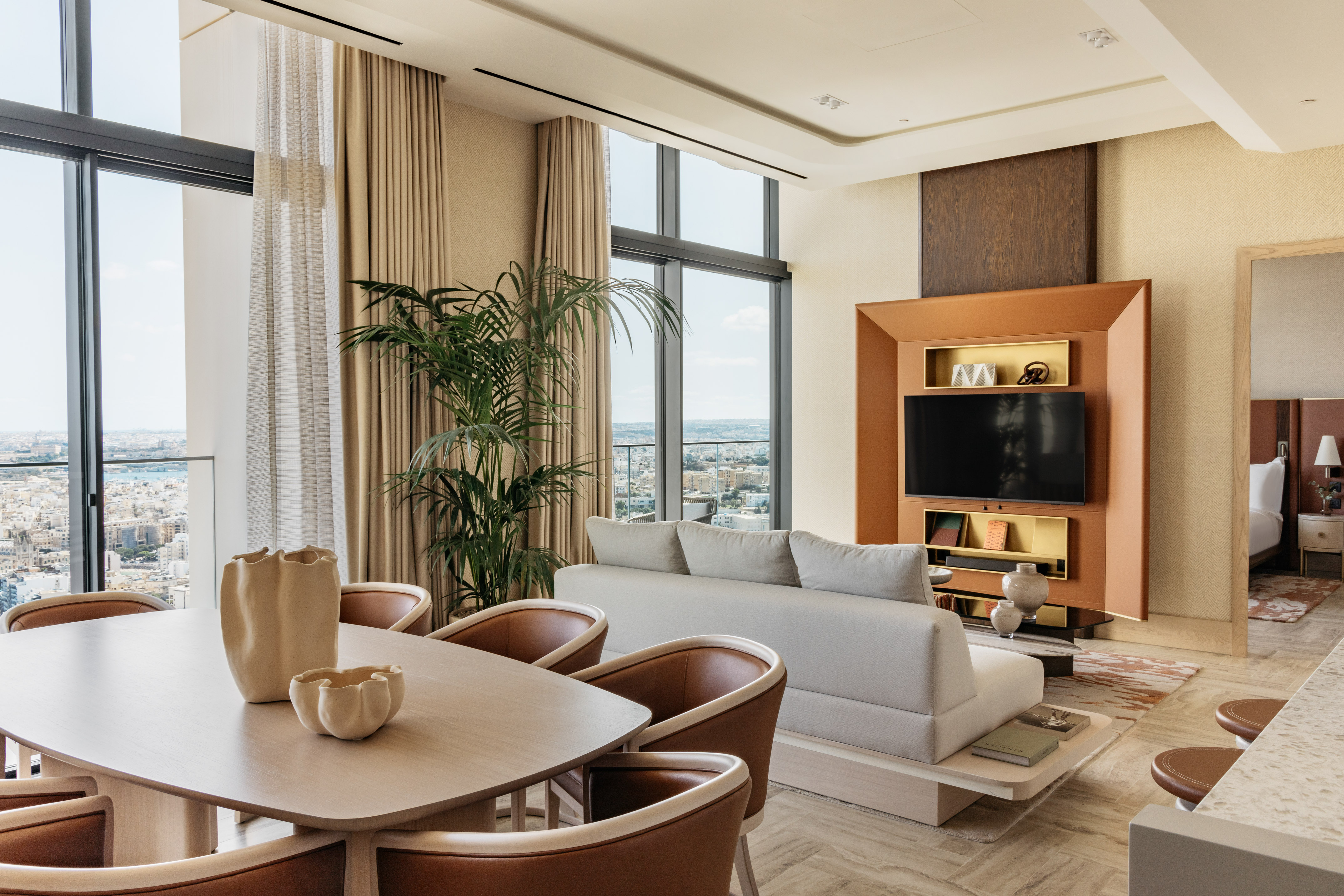 Elegant living-dining area in a modern suite with panoramic city views.