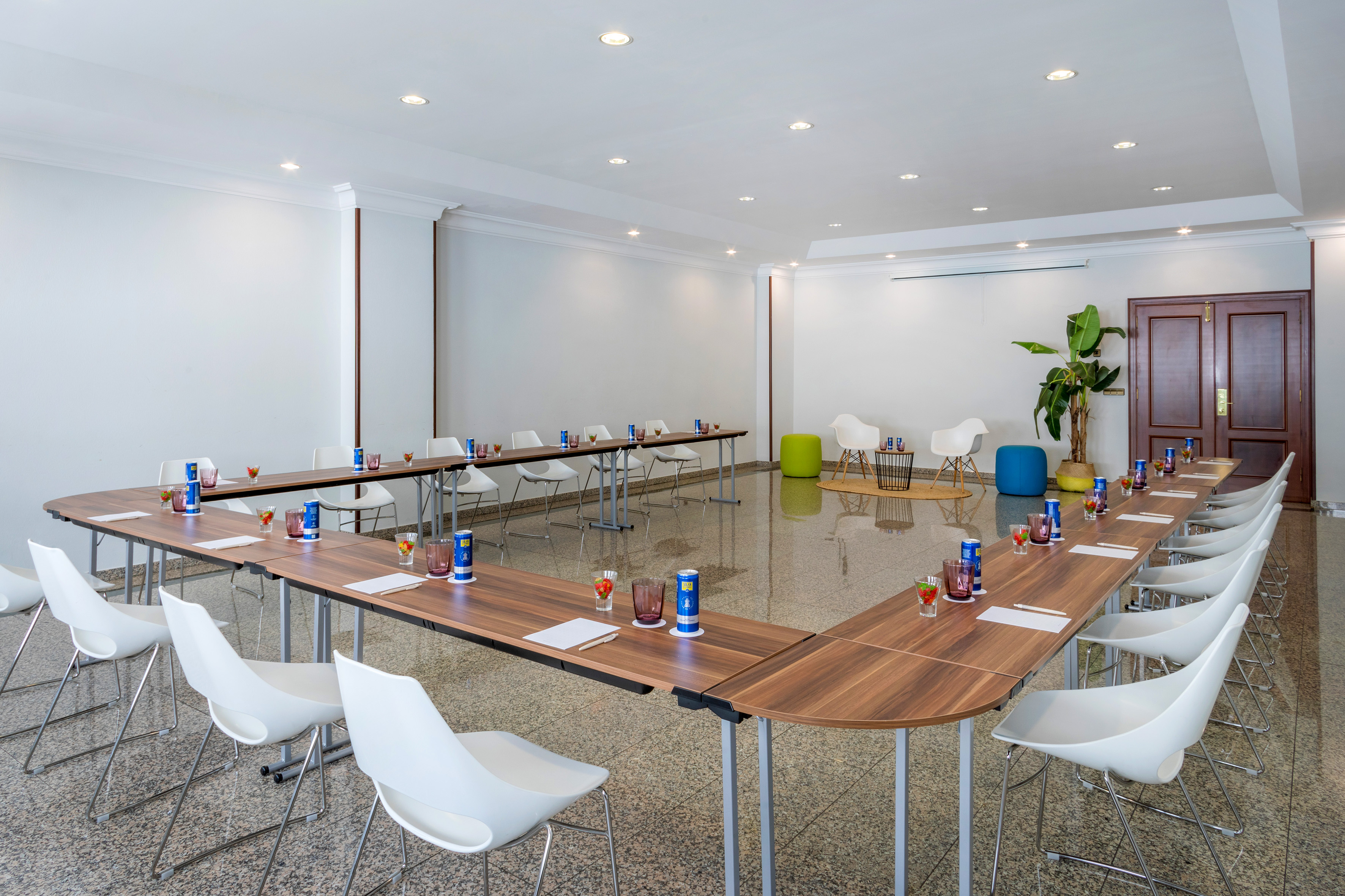 Modern U-shaped conference room with white chairs and wooden tables.