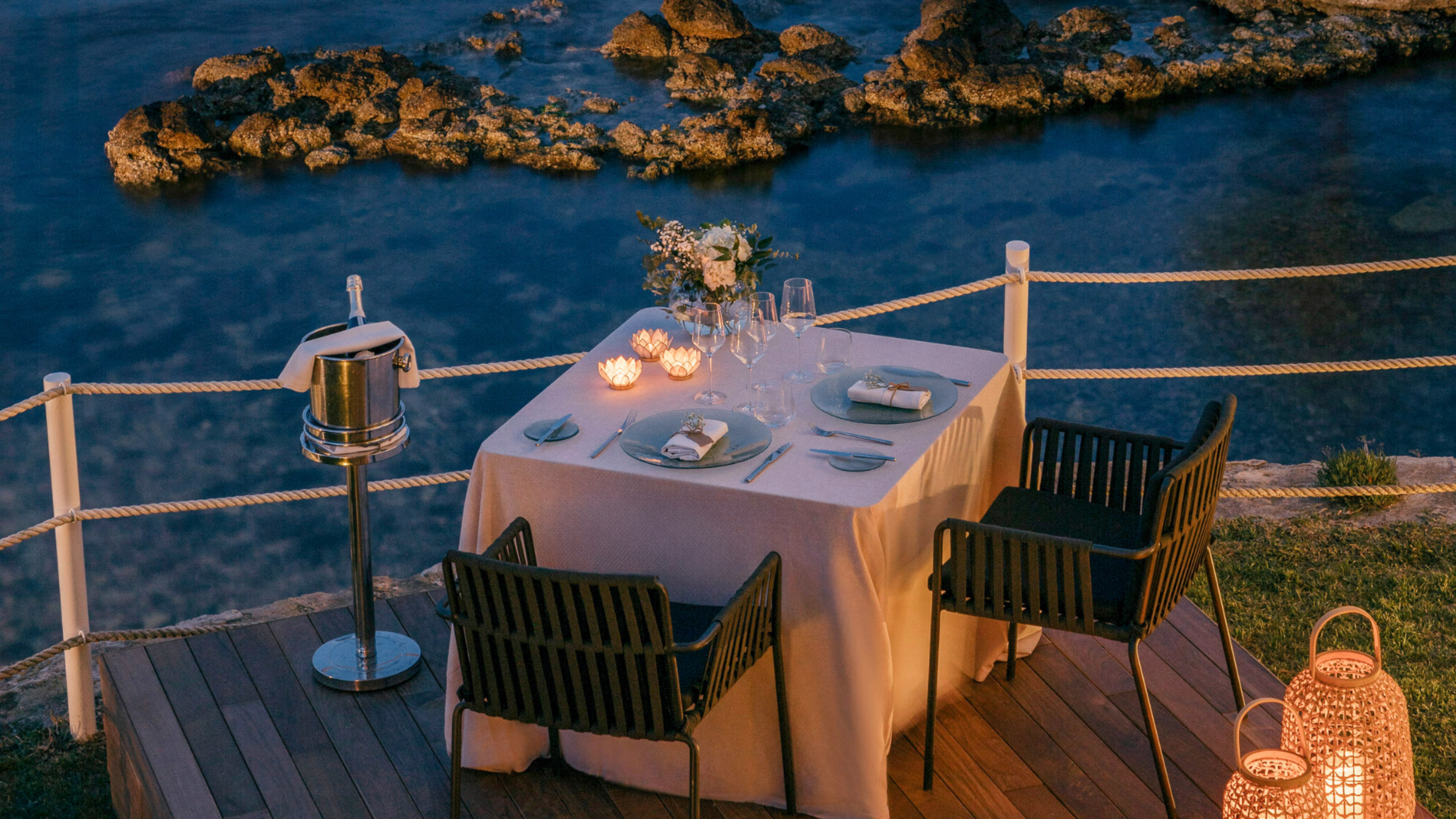 Luxurious sunset dinner table on a deck overlooking the sea.