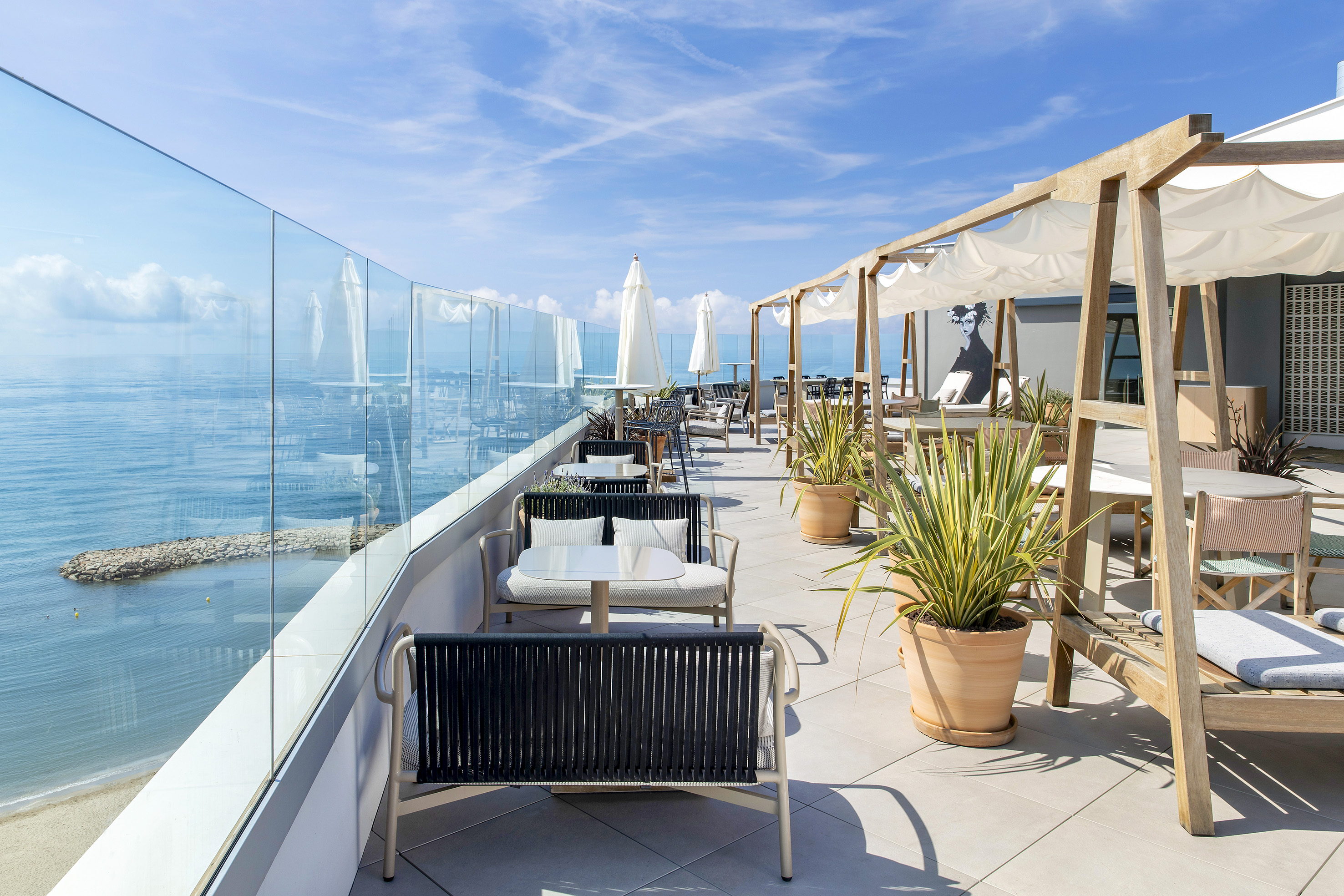 Coastal rooftop terrace with ocean view, outdoor dining, and comfortable seating.