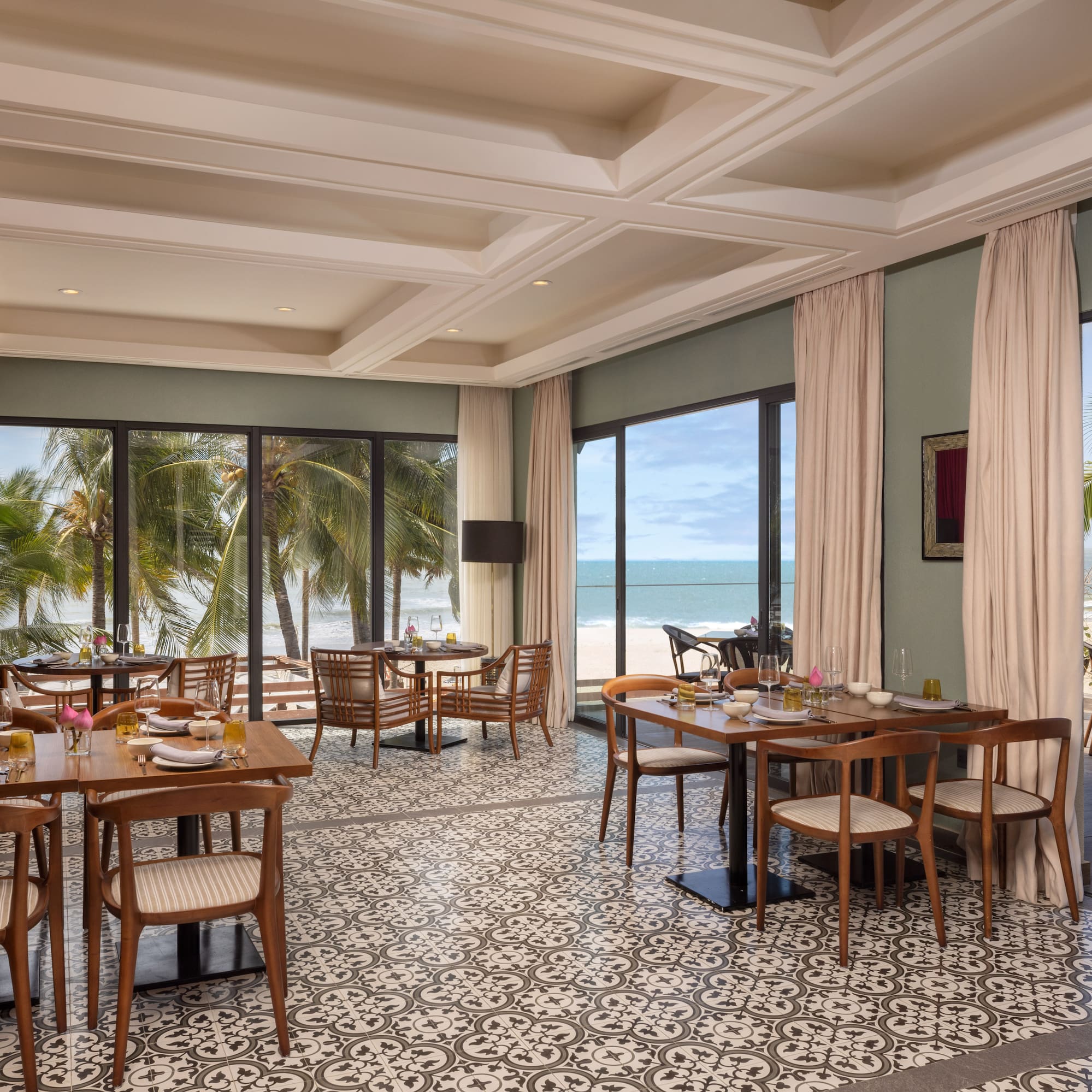 a room with tables and chairs and a view of the ocean