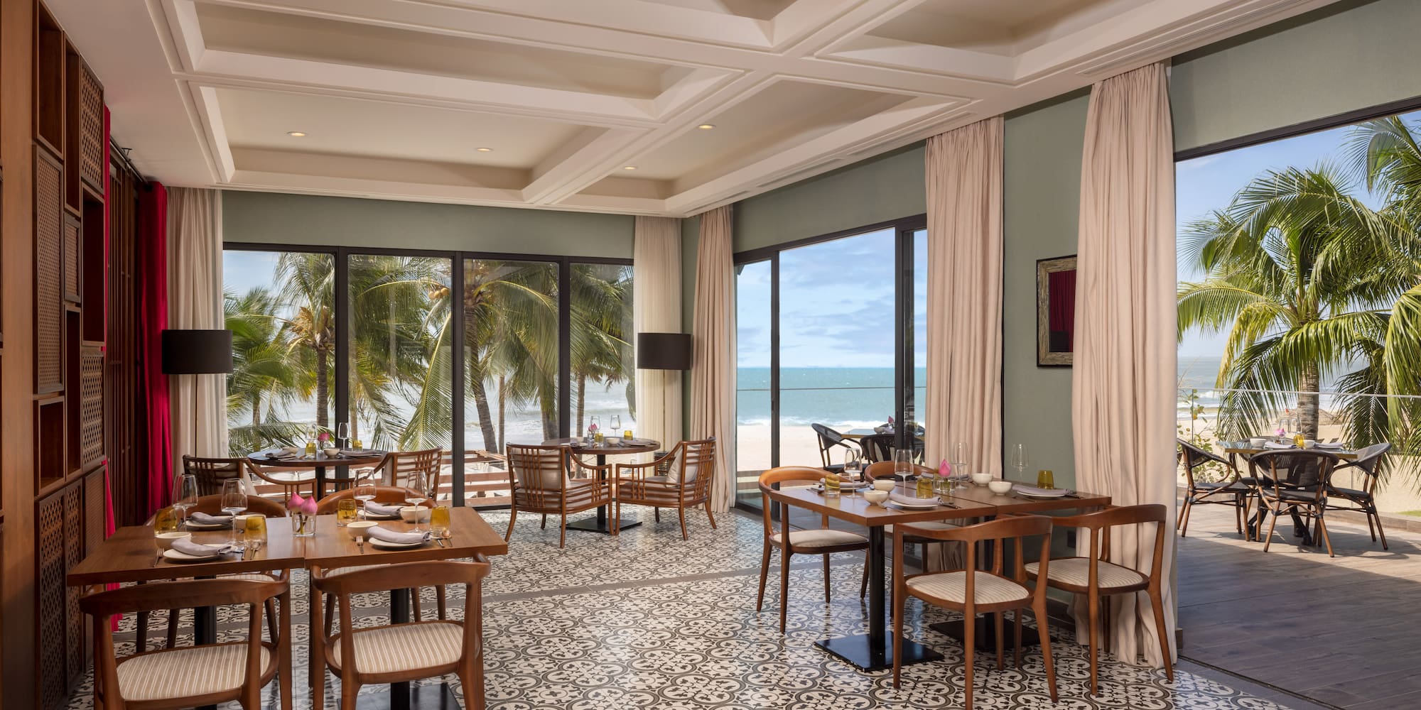 a room with tables and chairs and a view of the ocean