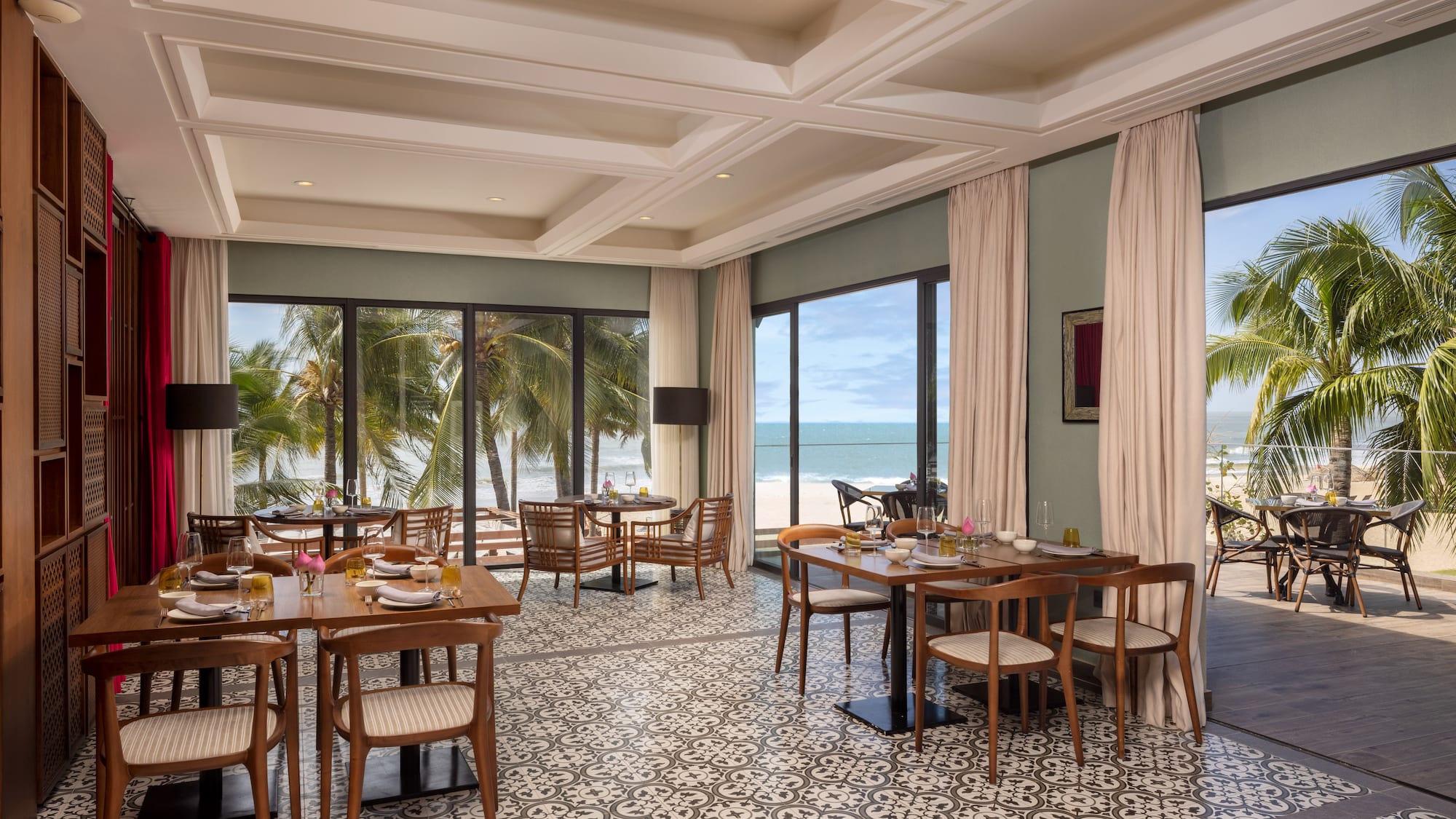 a room with tables and chairs and a view of the ocean