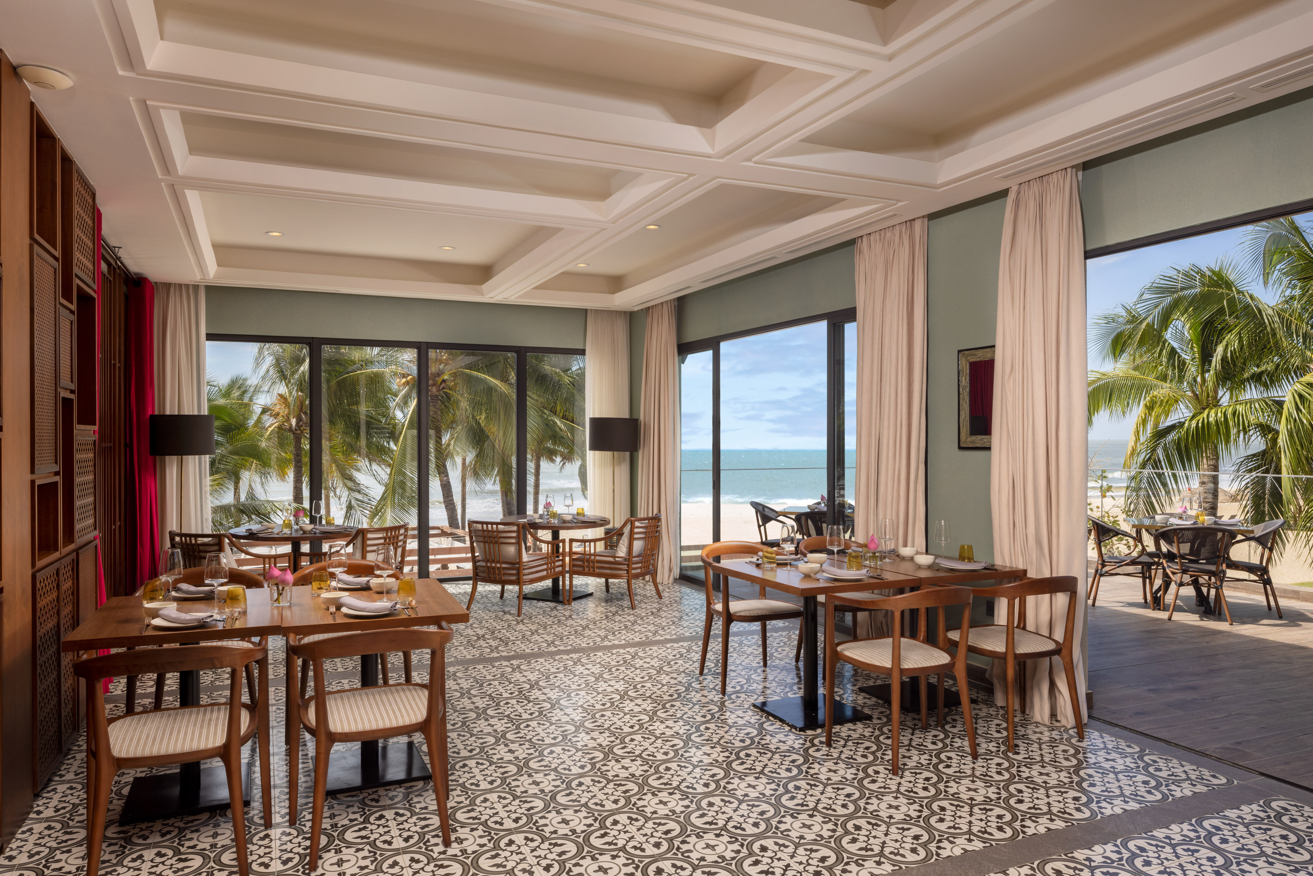 Tropical beach view restaurant with patterned tiled floor and outdoor seating.