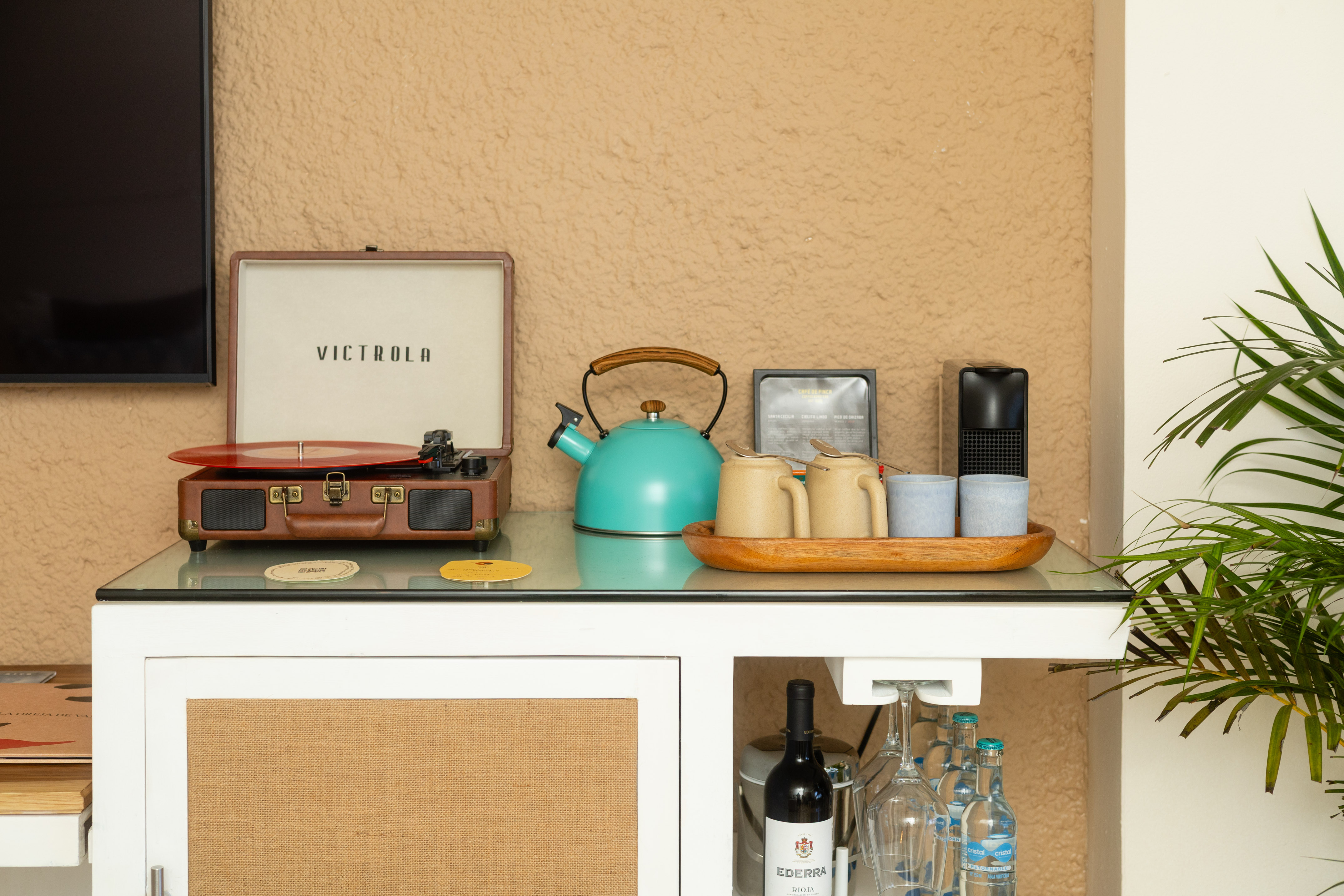 Retro Victrola record player, teal kettle, coffee cups, and minibar setup.