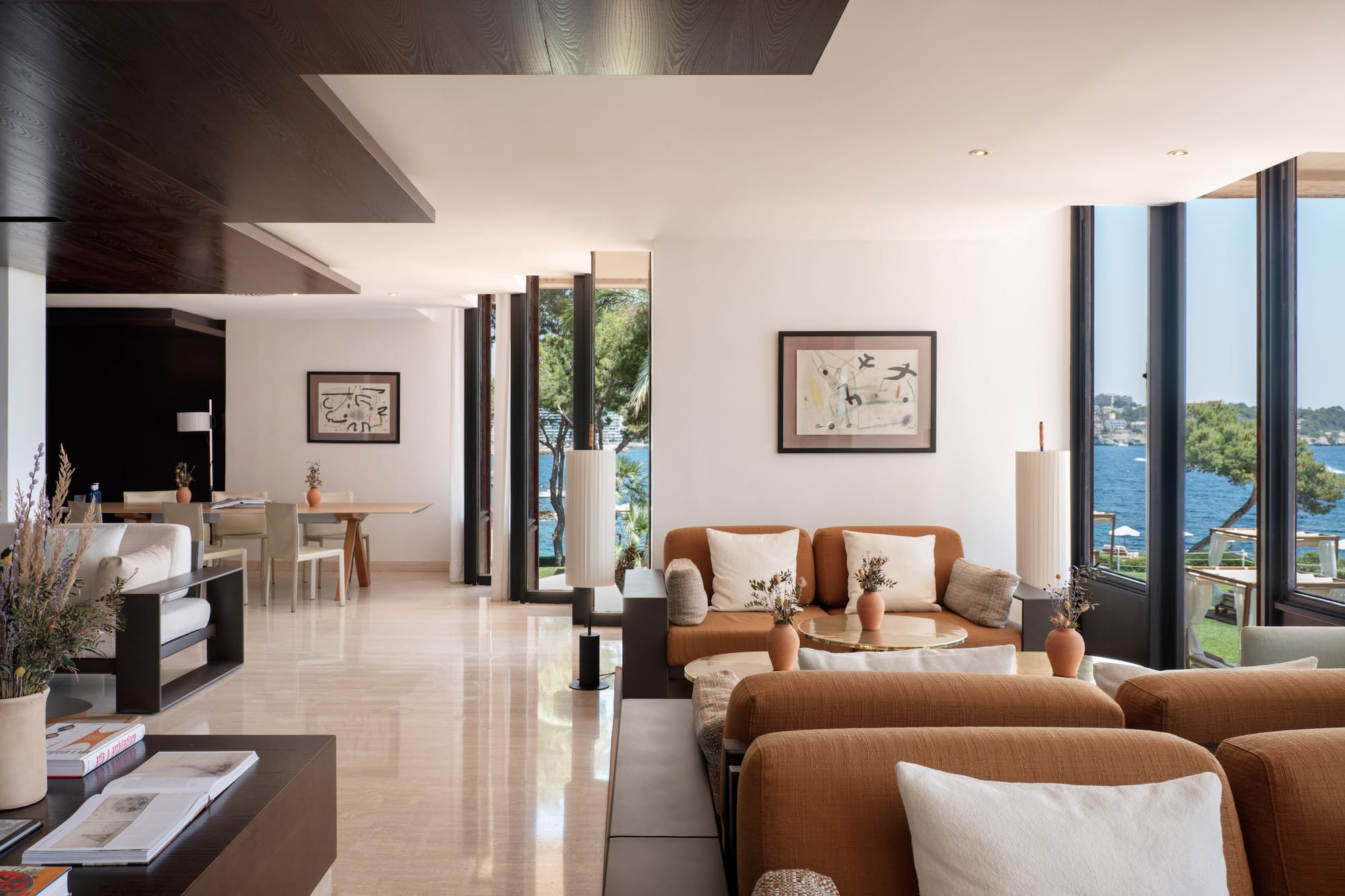 Coastal luxury living room with ocean view, brown sofas, modern design.