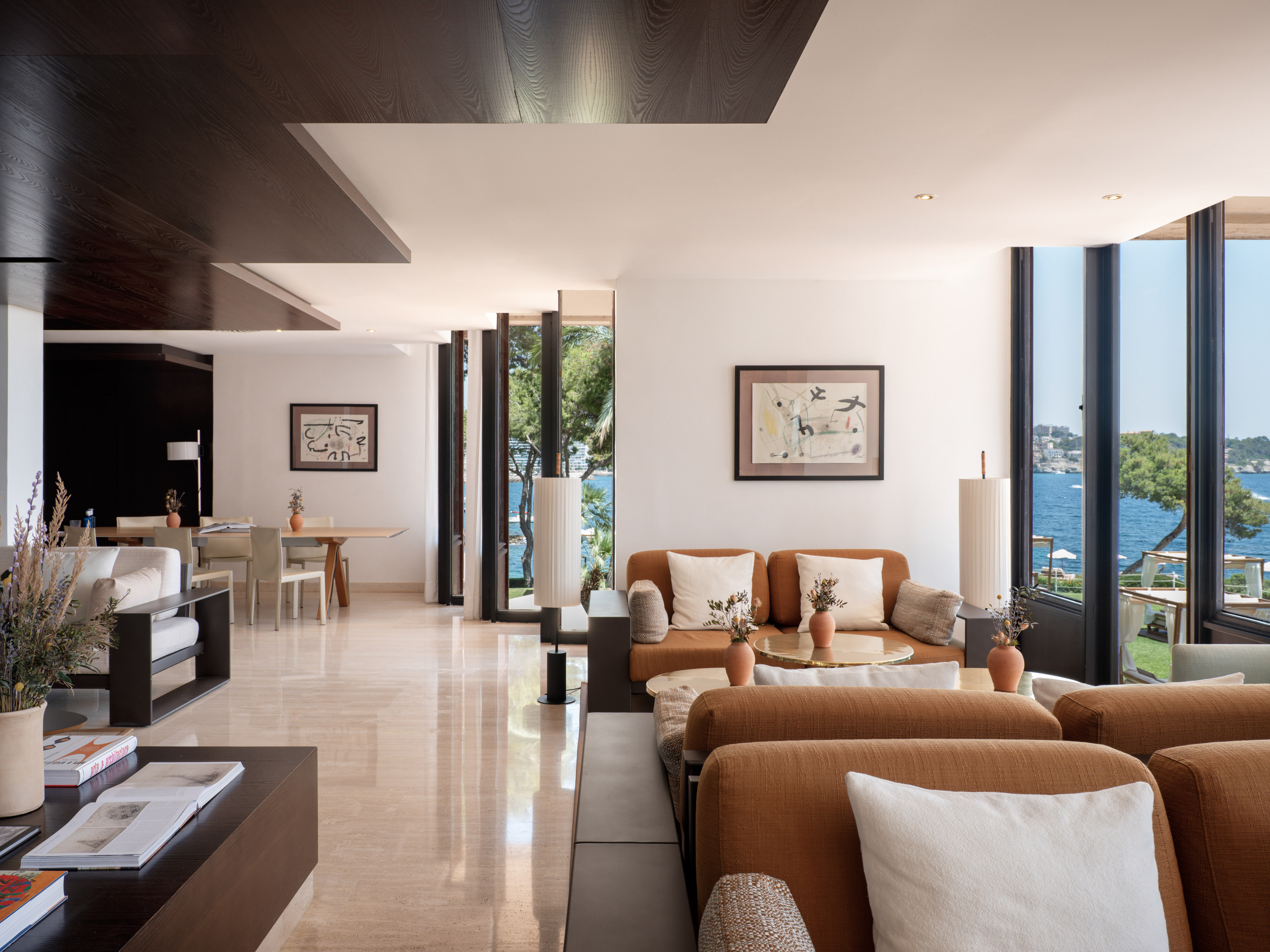 Coastal luxury living room with ocean view, brown sofas, modern design.