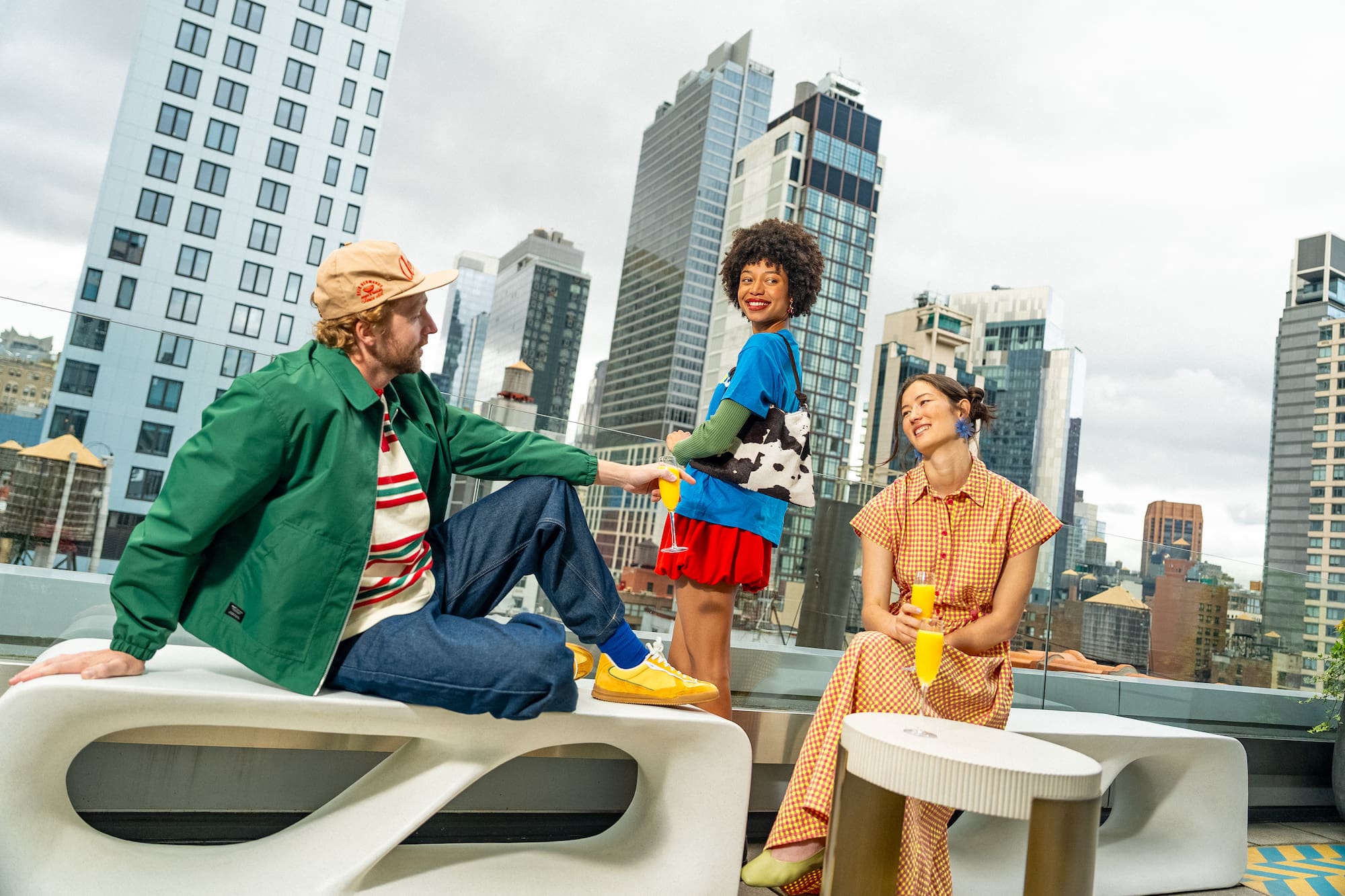 Stylish friends on a city rooftop, enjoying drinks with urban skyline views.