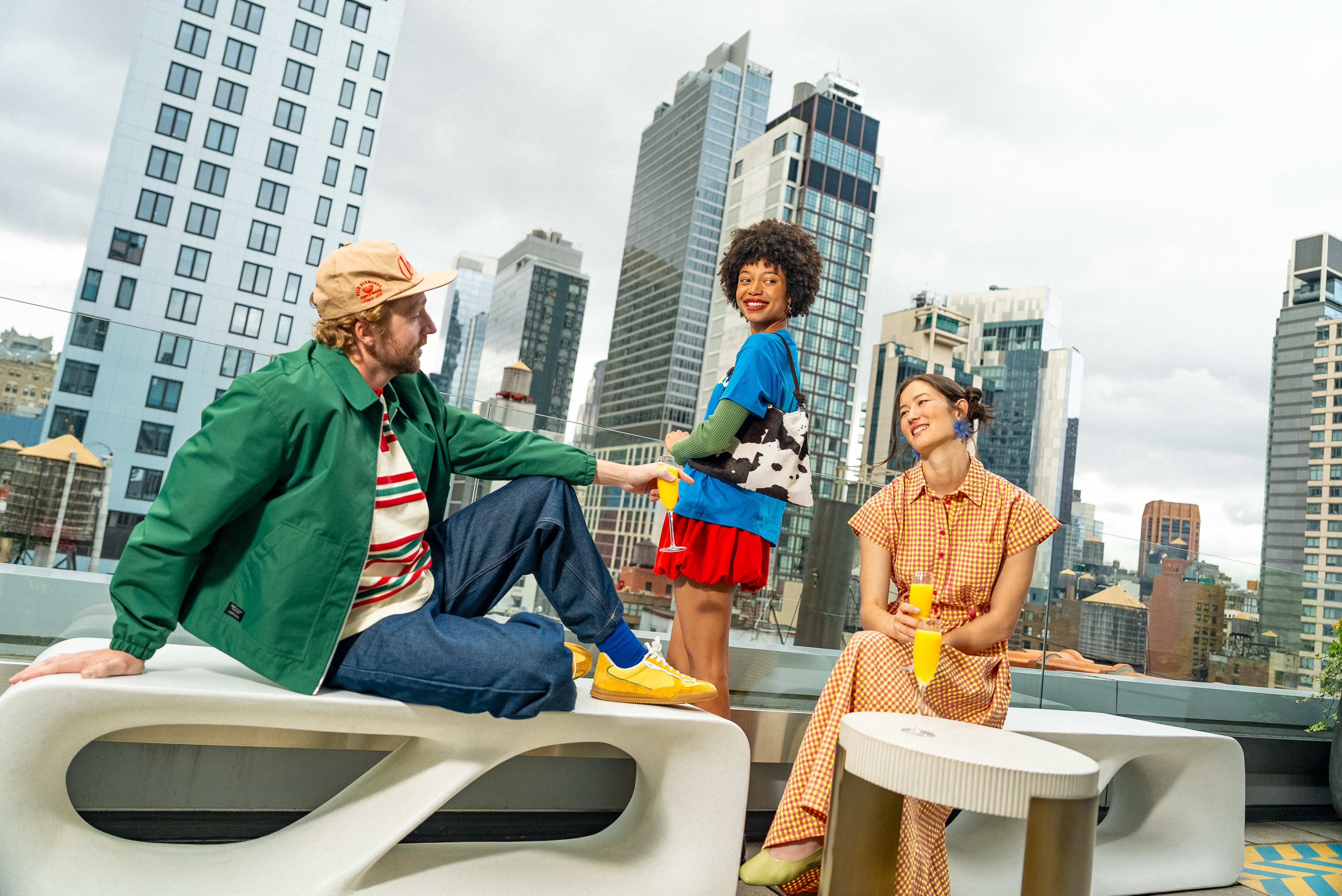 Stylish friends on a city rooftop, enjoying drinks with urban skyline views.
