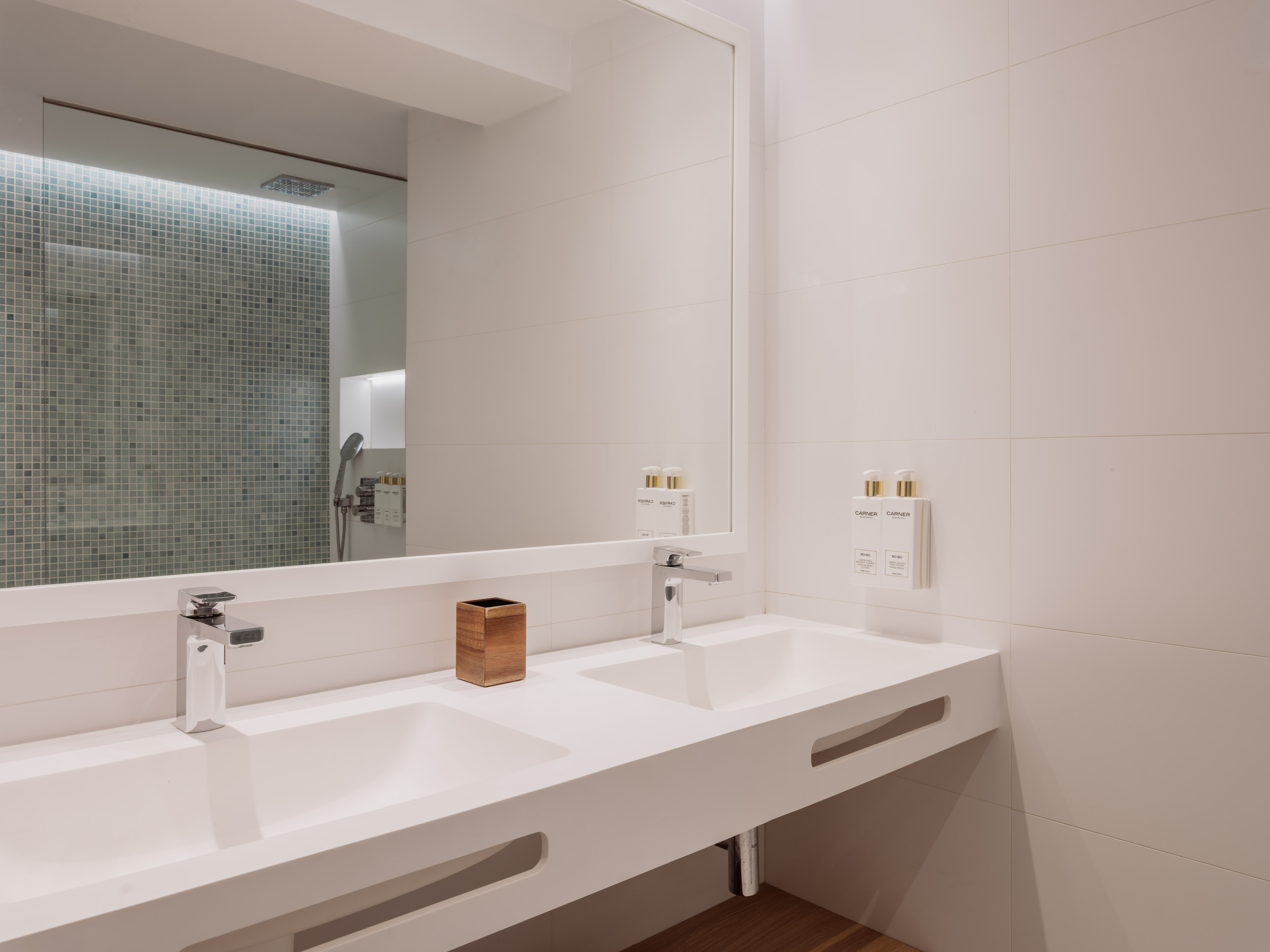 Baño moderno con lavabo doble blanco, grifos cromados y ducha de azulejos.