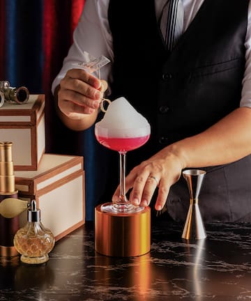 a person pouring a drink into a glass