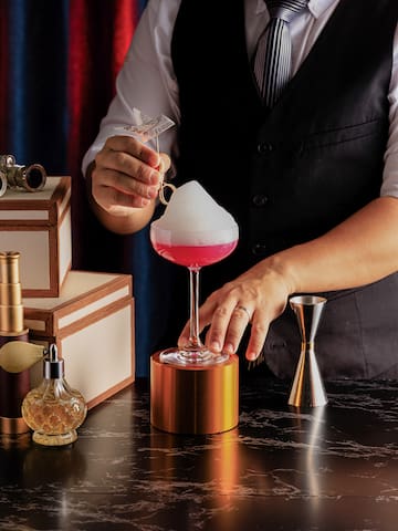 a person pouring a drink into a glass