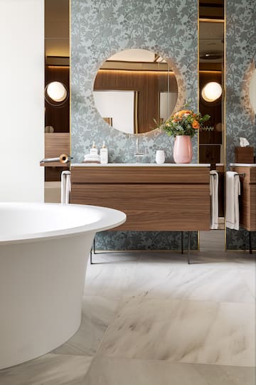 a bathroom with a round mirror and a tub