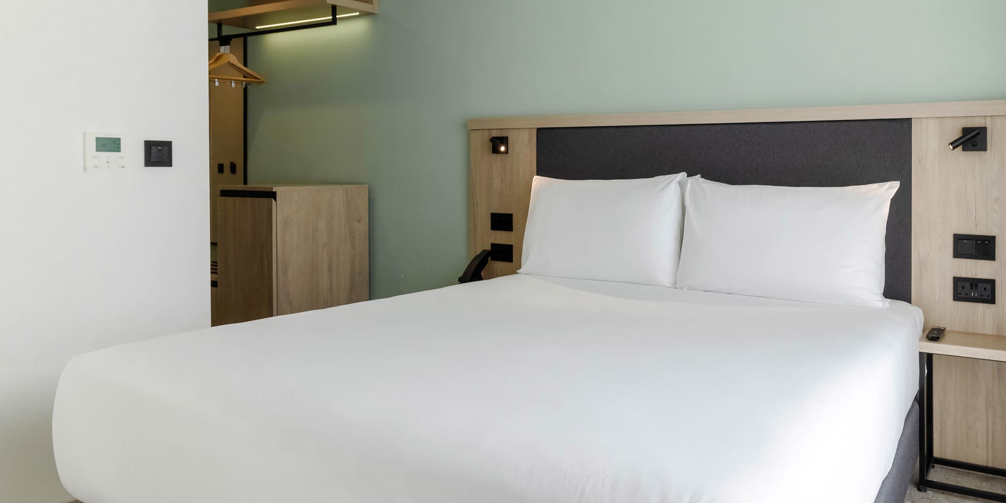 a bed with white sheets and a wooden headboard