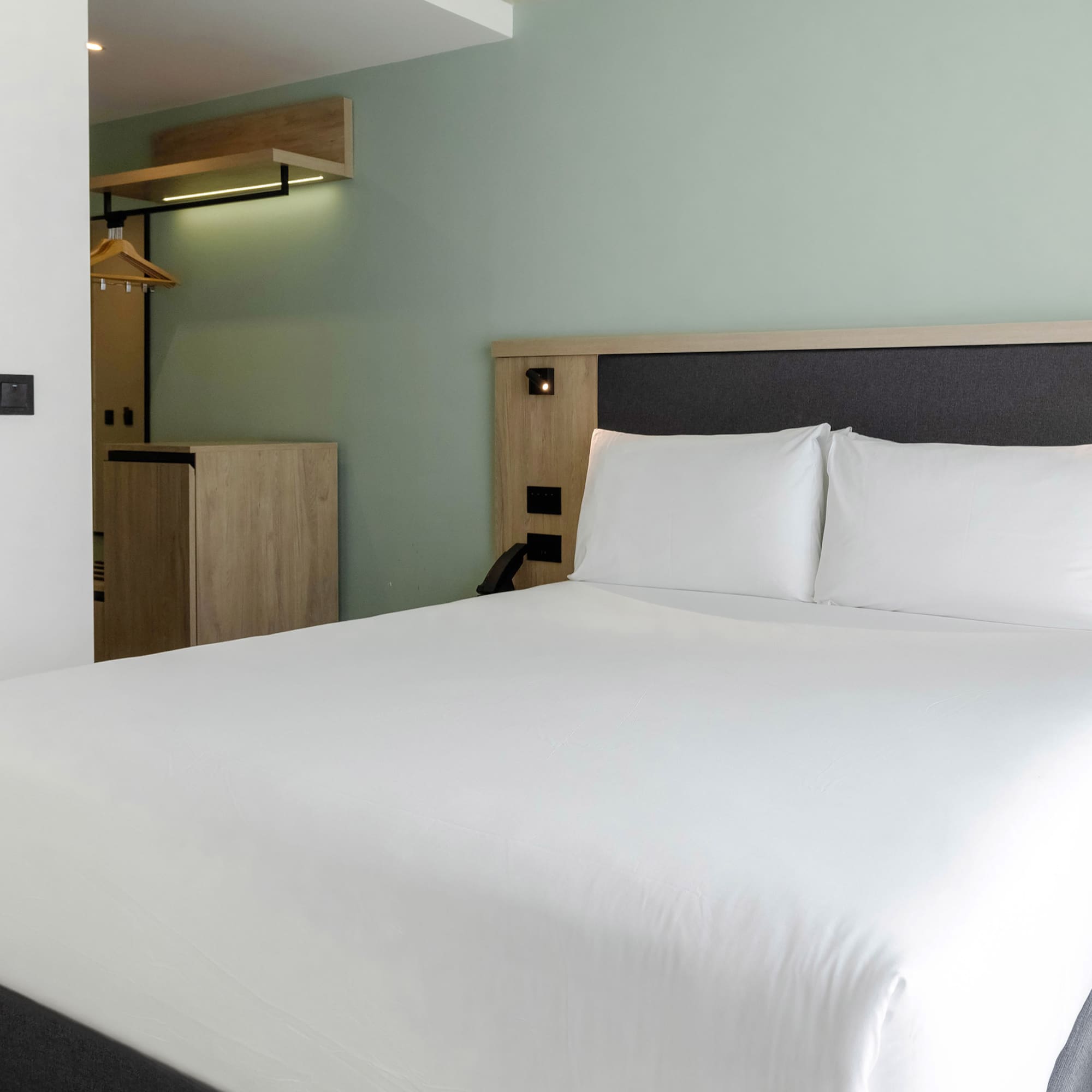 a bed with white sheets and a wooden headboard