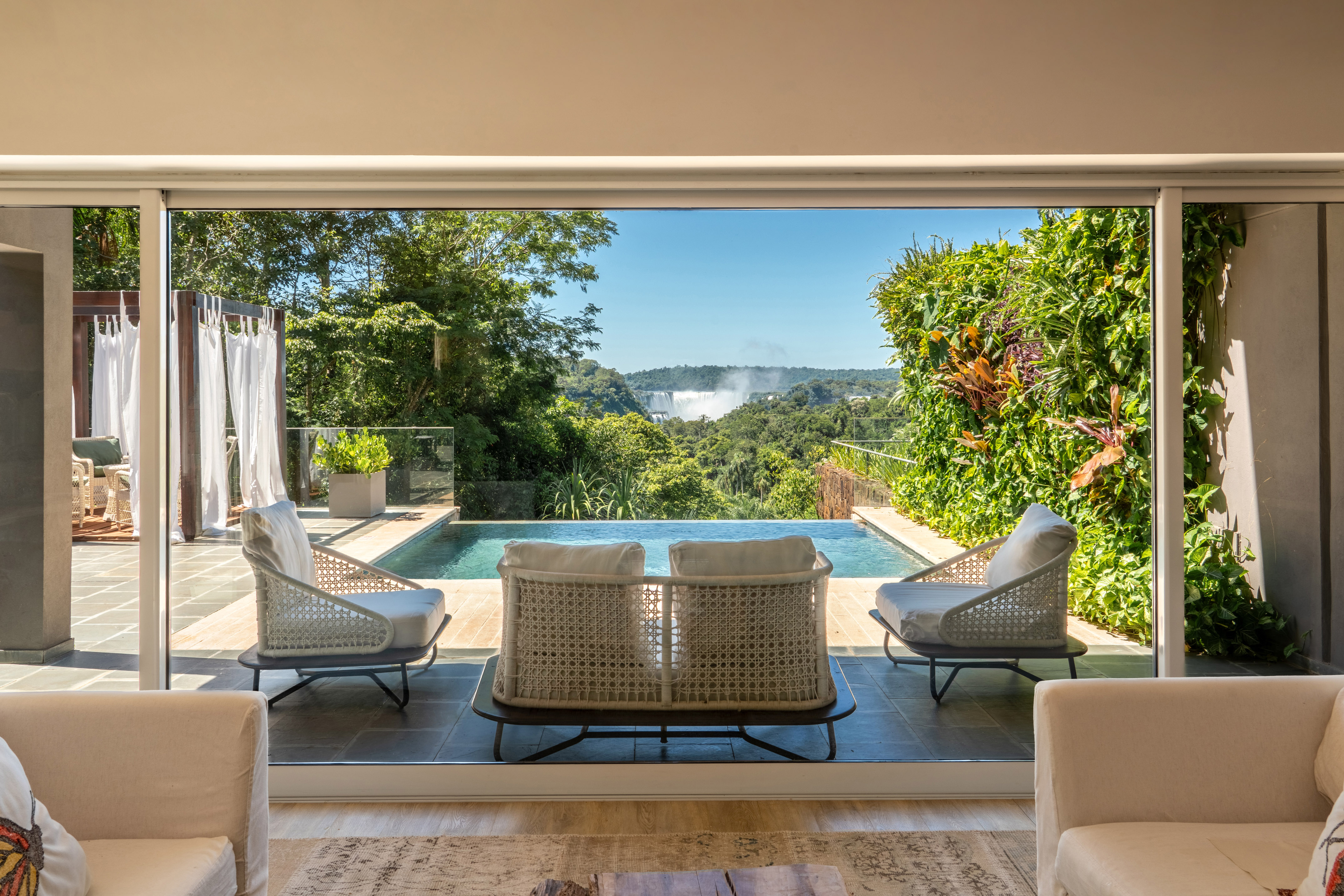 Luxury patio with infinity pool, jungle view, and distant Iguazu Falls.