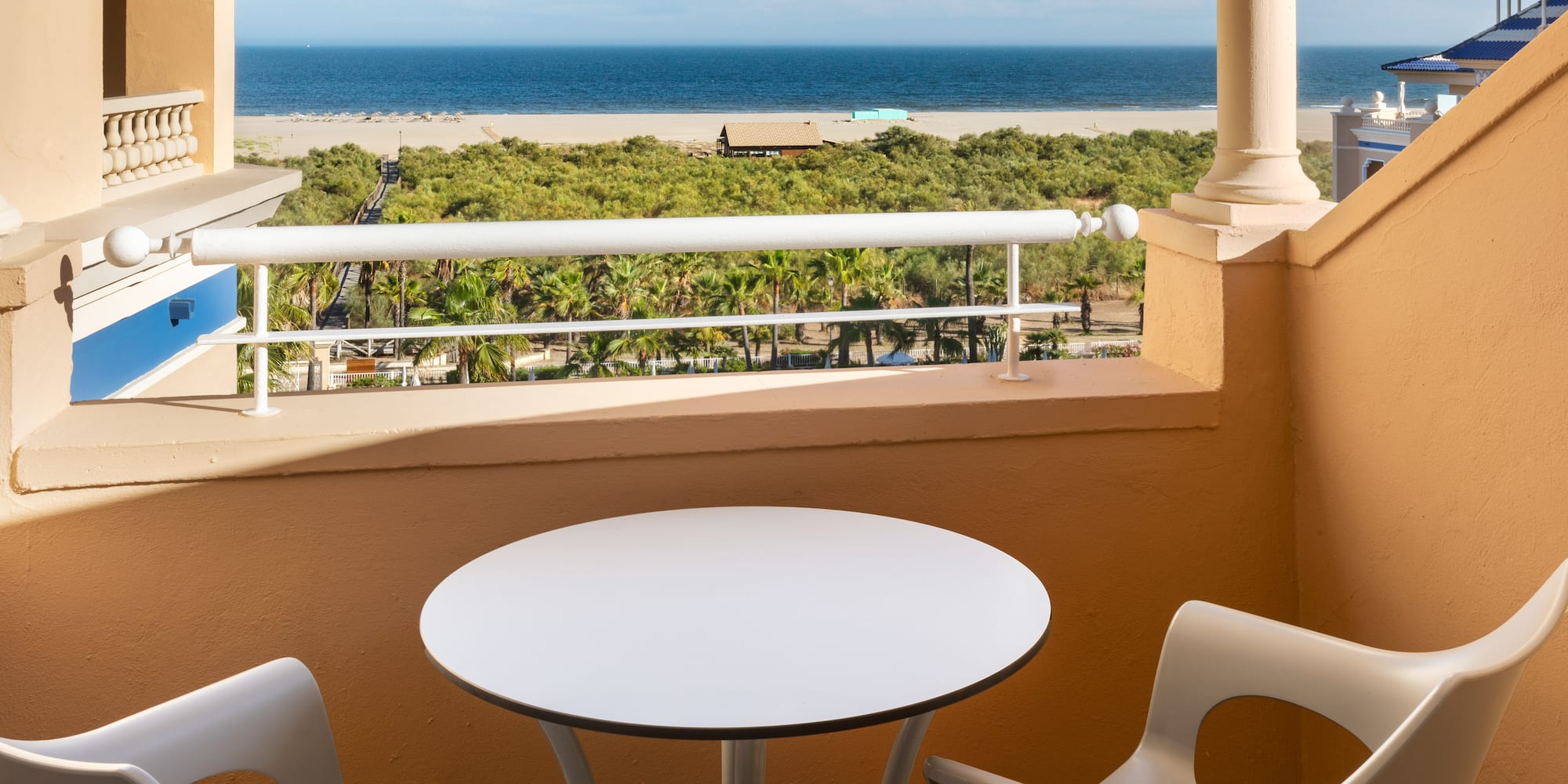 a table and chairs on a balcony overlooking a beach
