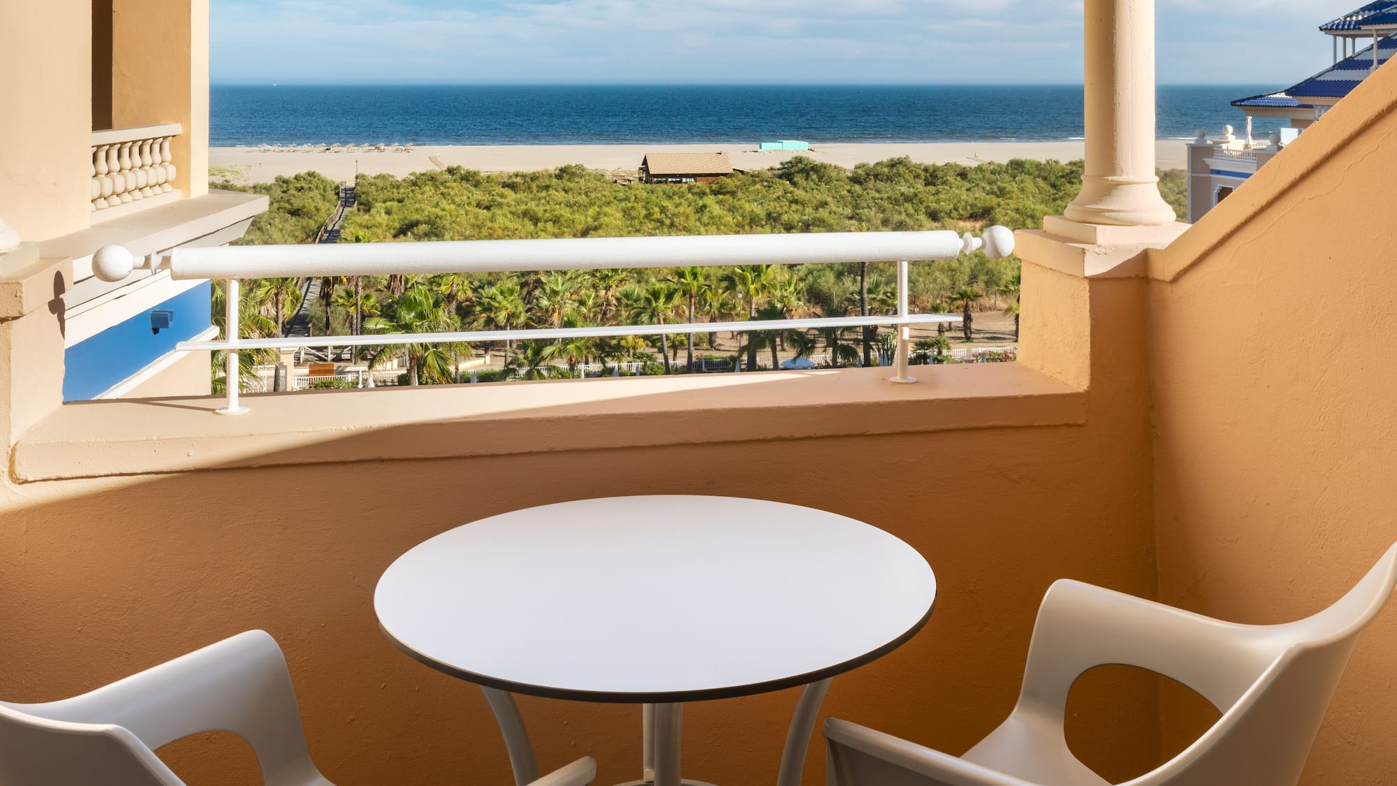 a table and chairs on a balcony overlooking a beach