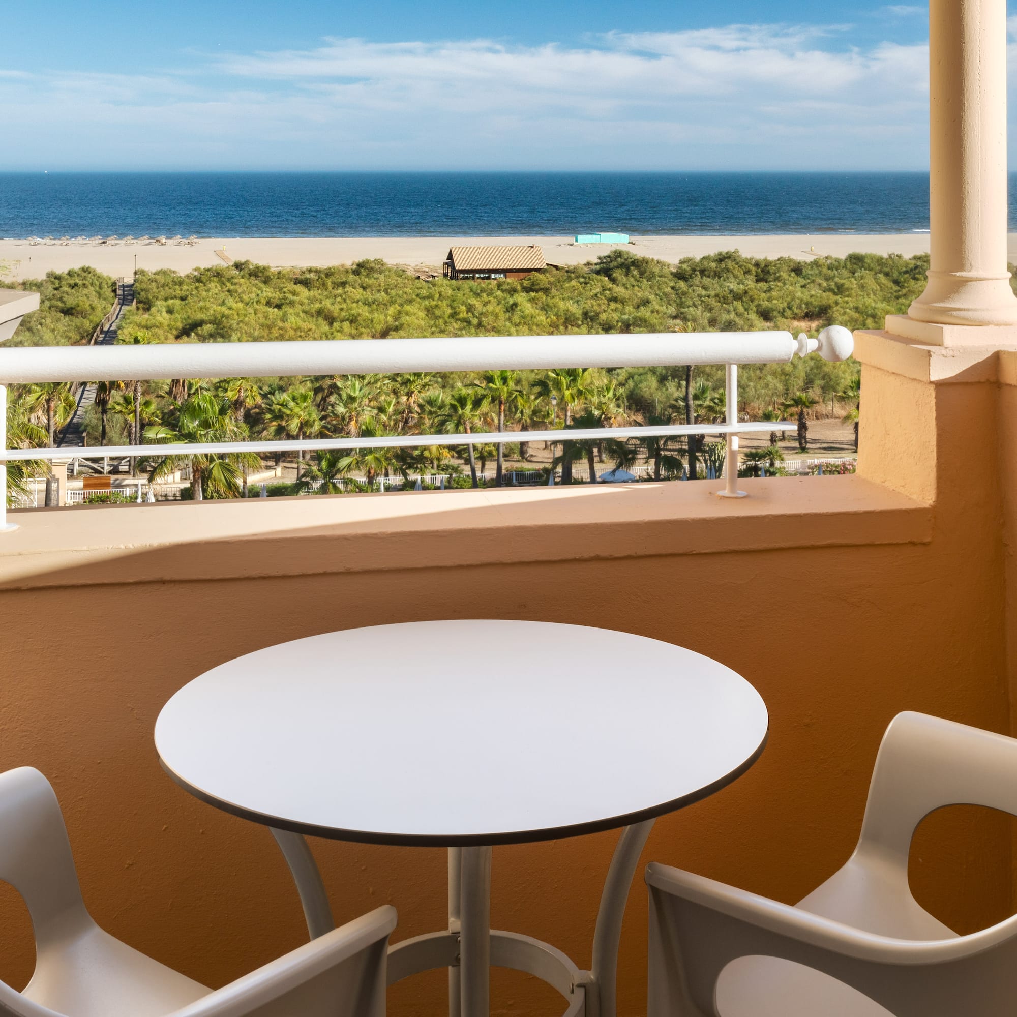 a table and chairs on a balcony overlooking a beach