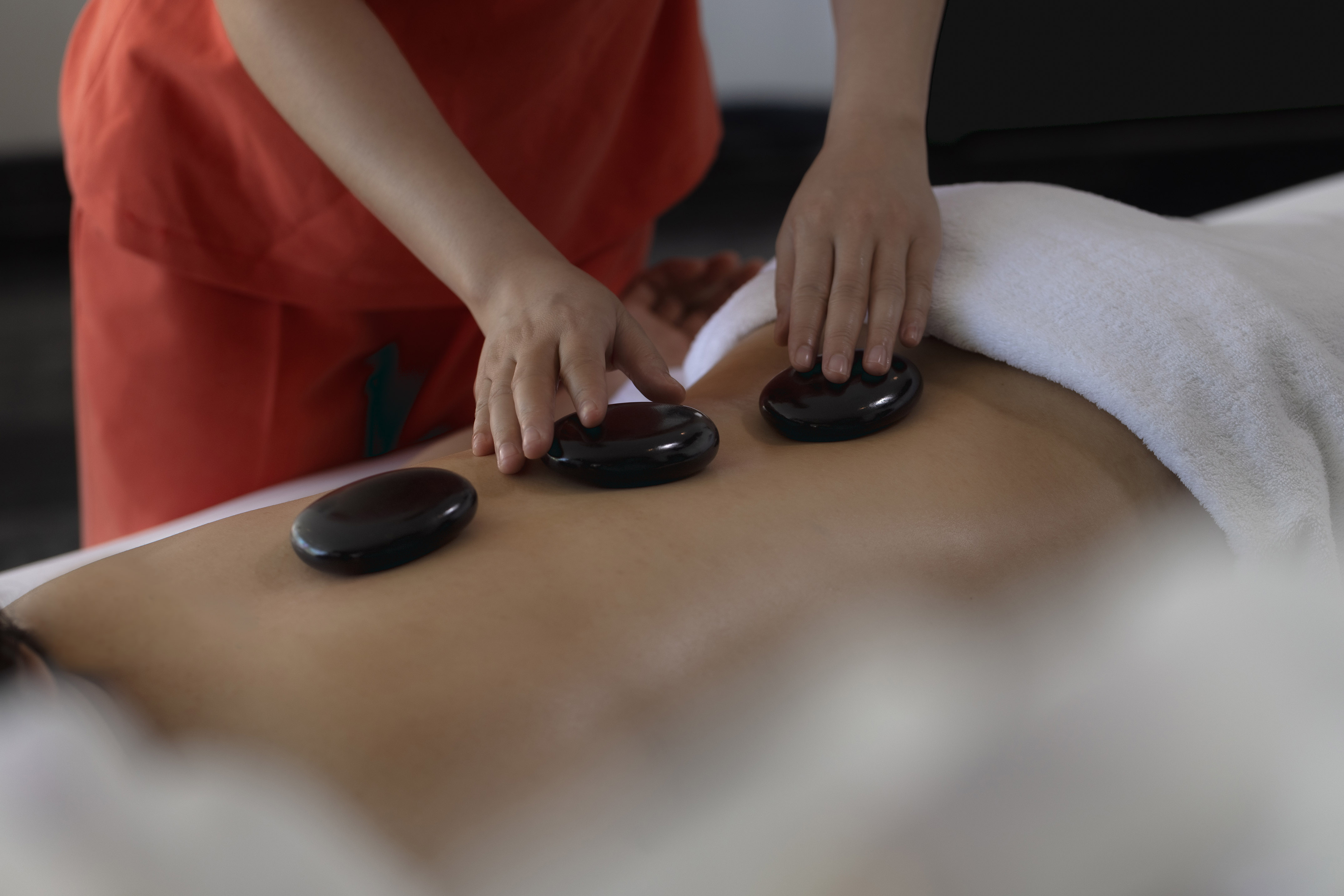 Relaxing hot stone back massage therapy in a spa setting.