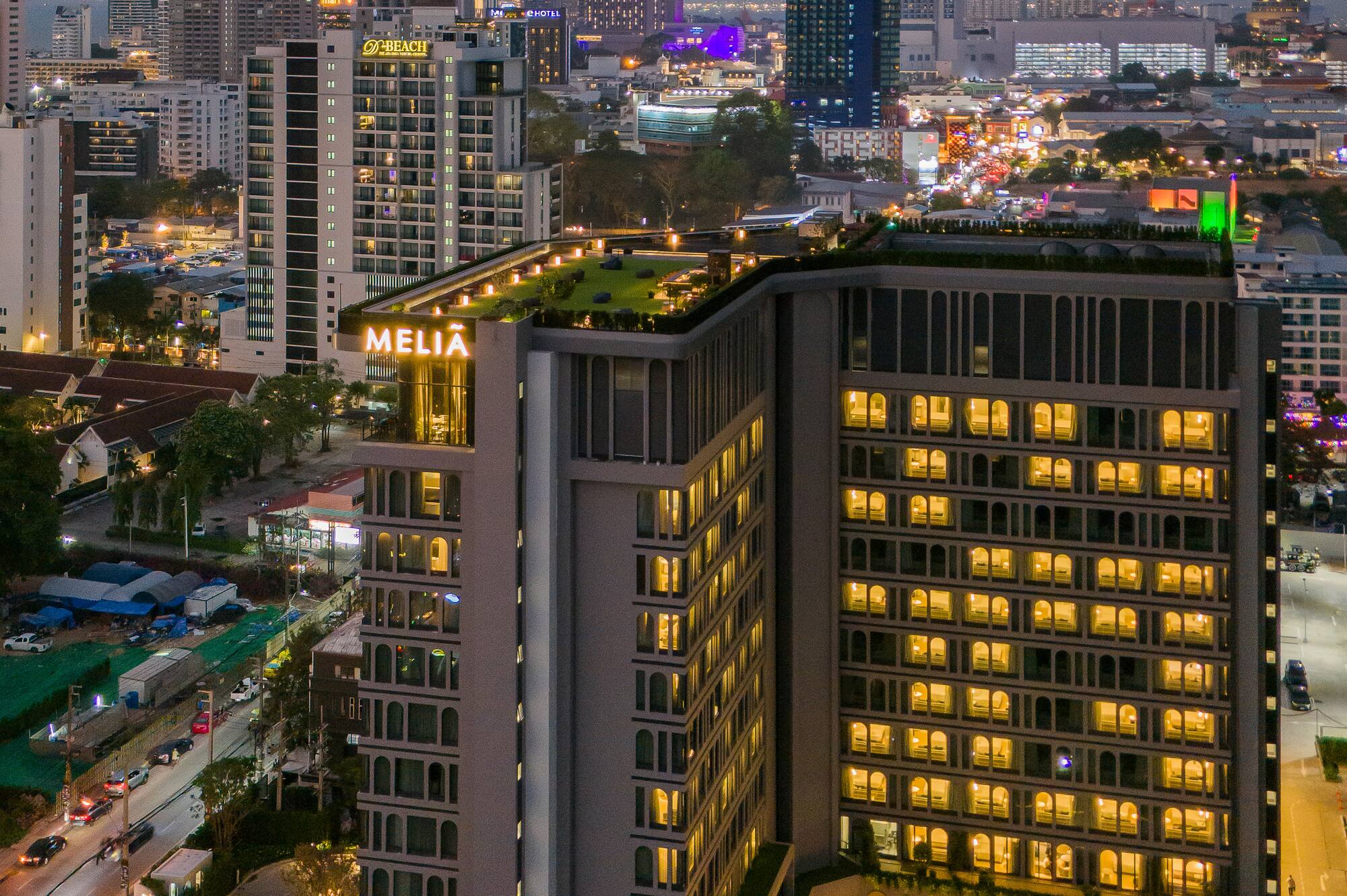 Meliá hotel illuminated at night against a vibrant city skyline.