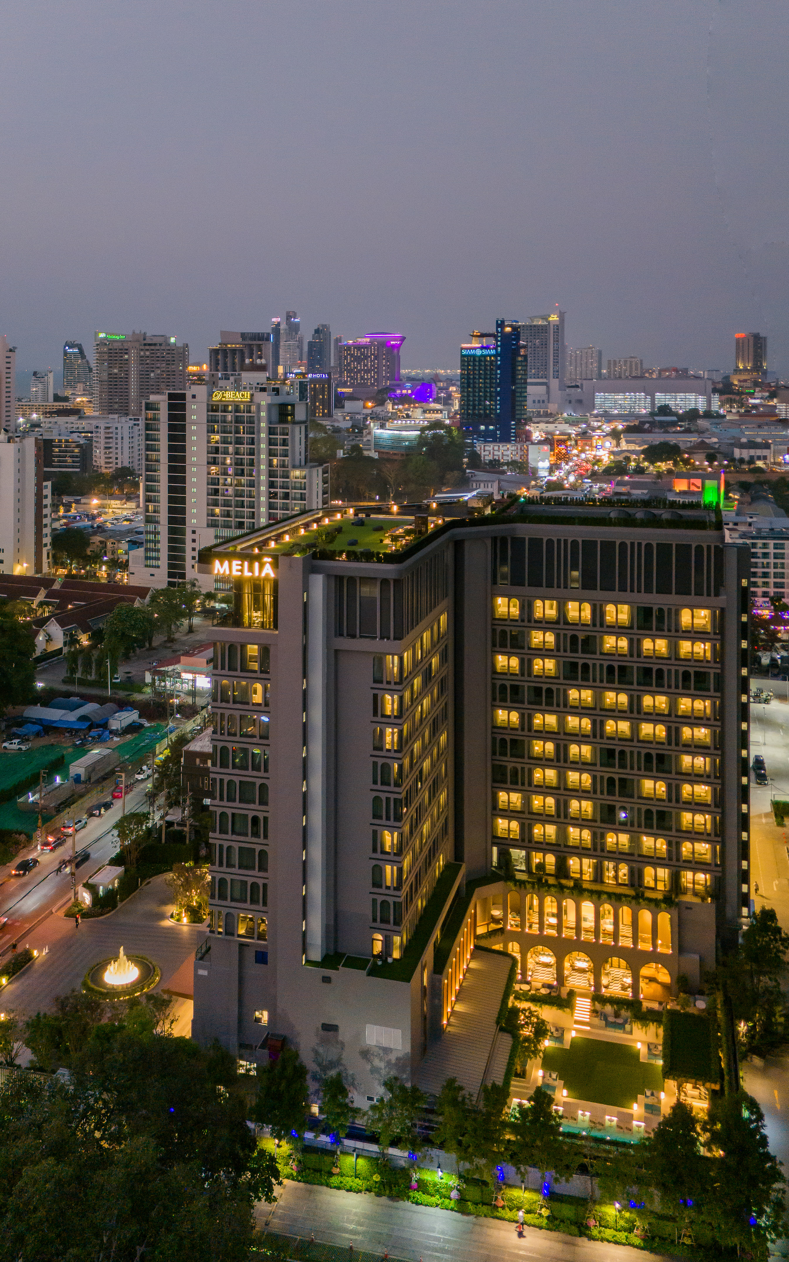 Meliá hotel illuminated at night against a vibrant city skyline.