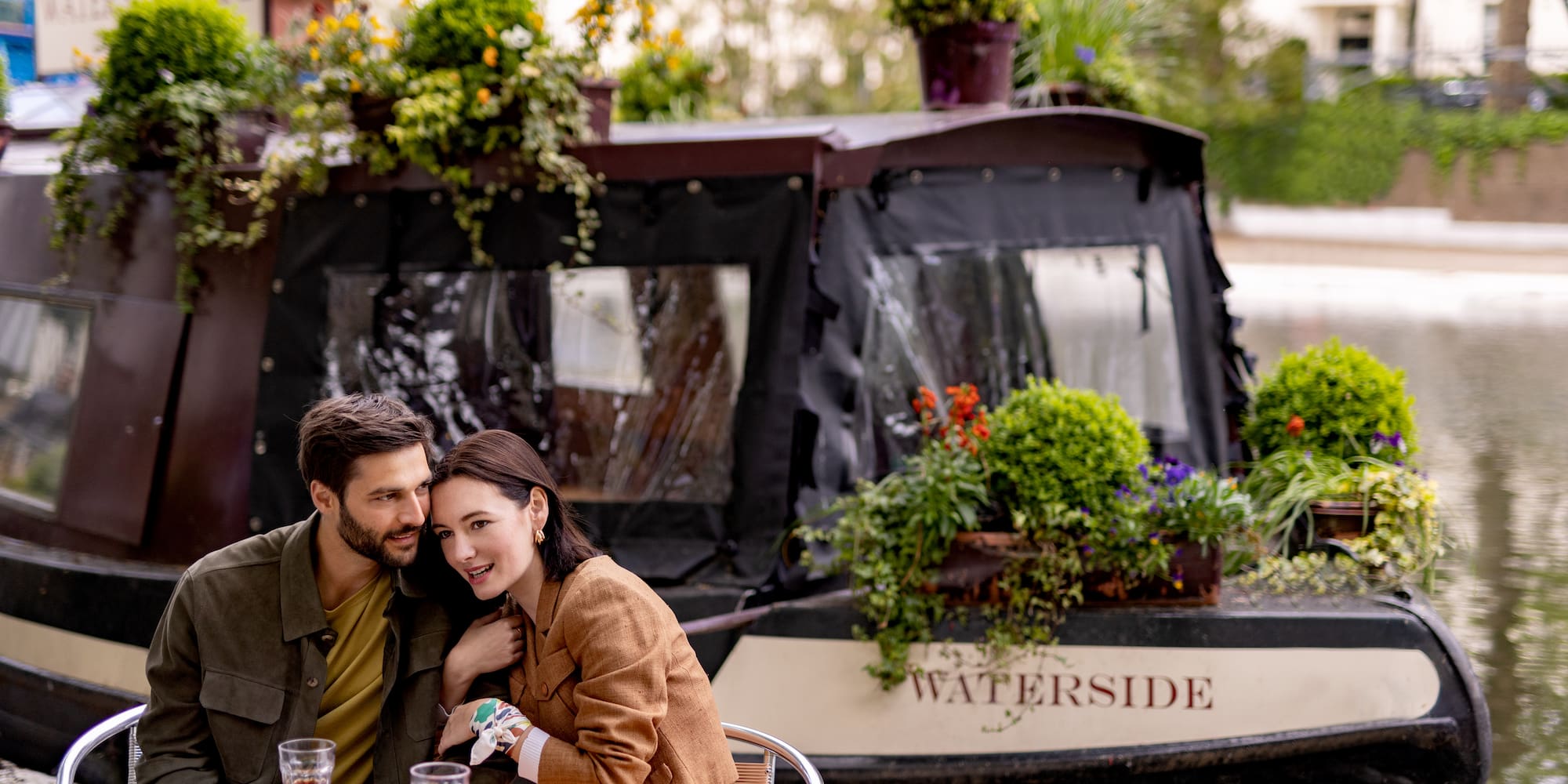 A man and woman are seated at a table, with plants beside them.