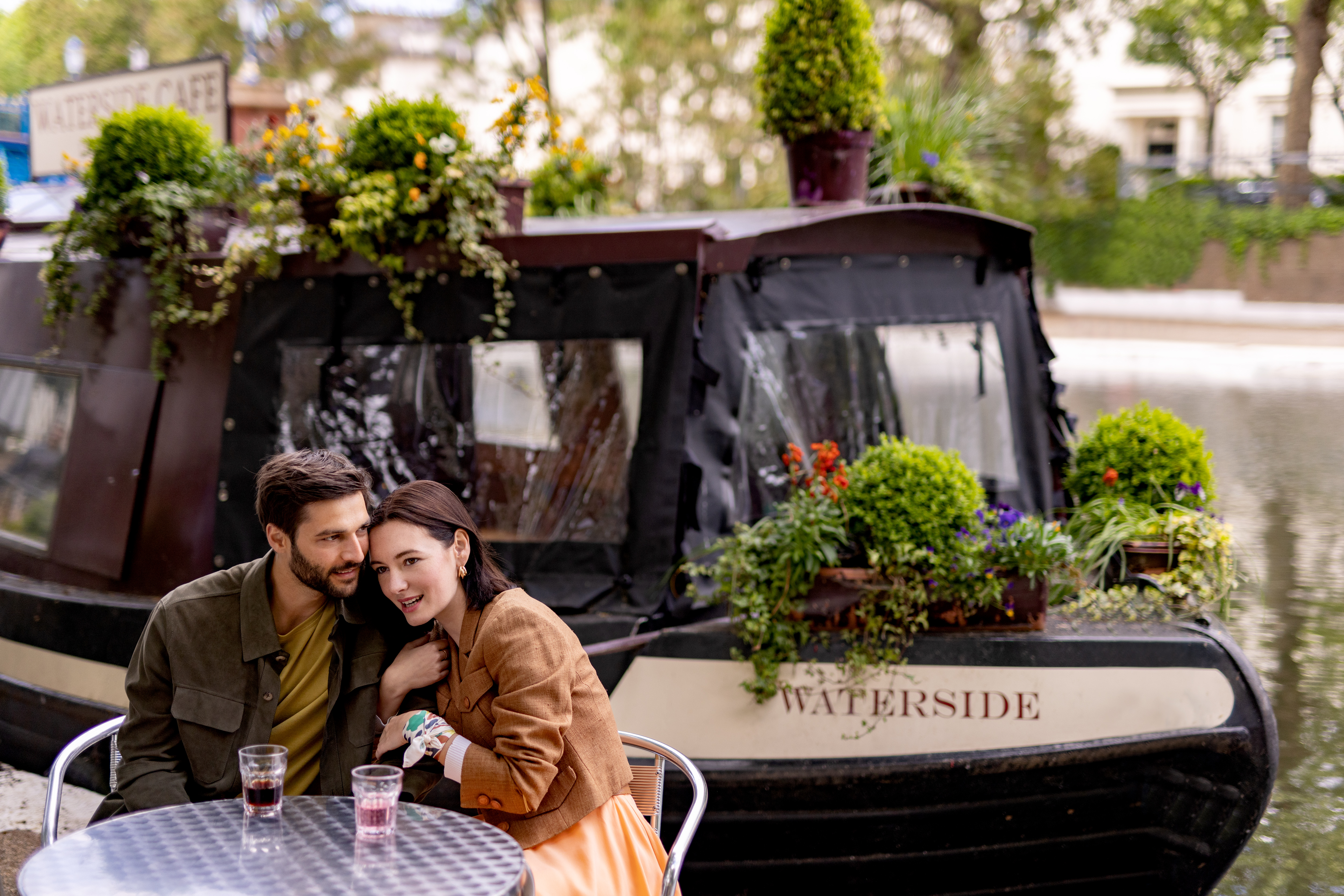 A man and woman are seated at a table, with plants beside them.