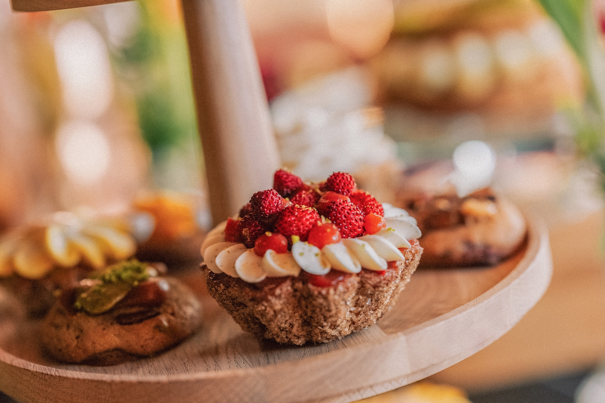 Stand de madera con tartaletas de fresas silvestres, cupcakes y postres variados.