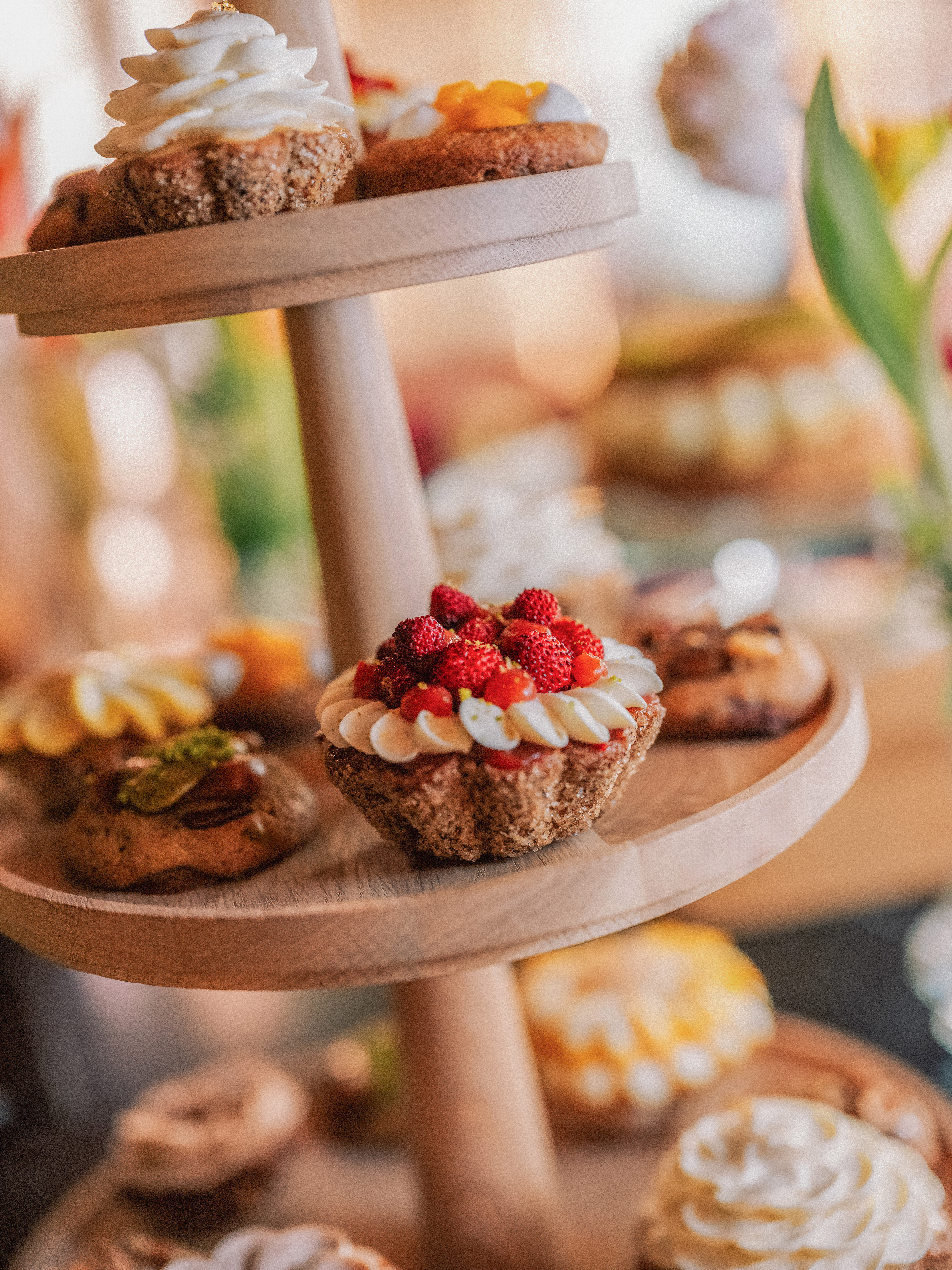 Wooden tiered stand with assorted mini tarts, wild strawberry tart in focus.
